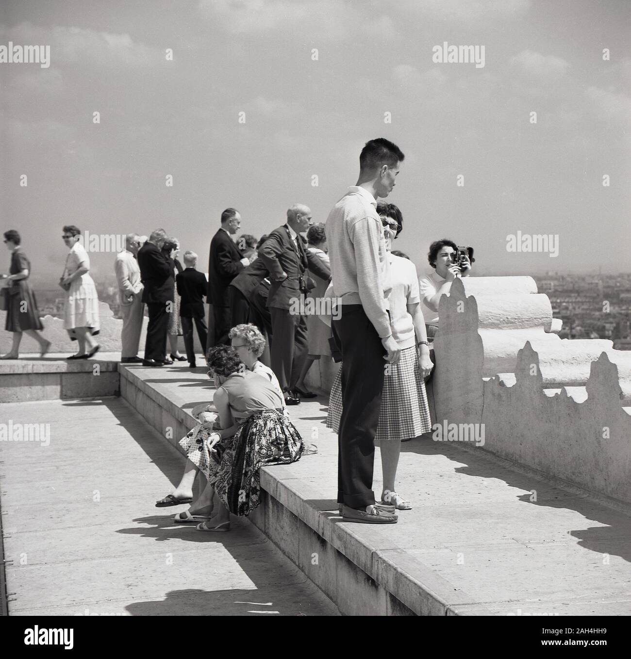 Années 1950, historiques, les touristes de la capitale debout sur un immeuble à la recherche sur Paris, France. Banque D'Images