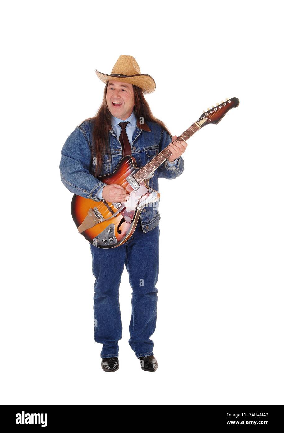 Un bel homme autochtone dans une veste, pantalon jeans et un chapeau de cowboy et permanent à jouer de la guitare, isolée pour fond blanc Banque D'Images