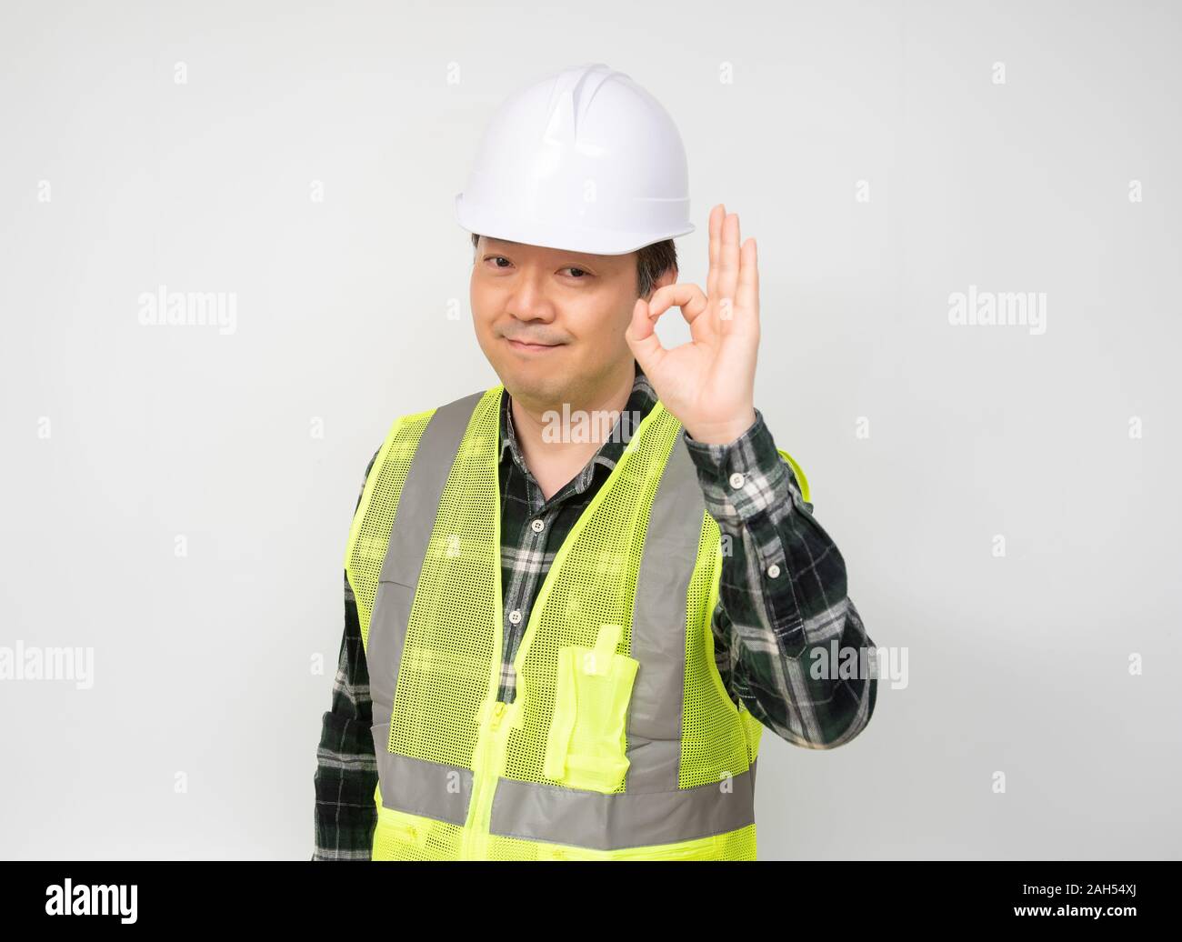 Un travailleur asiatique d'âge moyen lève la main et signes OK. Banque D'Images