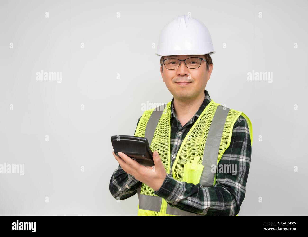 Un homme asiatique d'âge moyen portait un chapeau de travail Combinaison de travail et la tenue d'une calculatrice dans la main. Banque D'Images