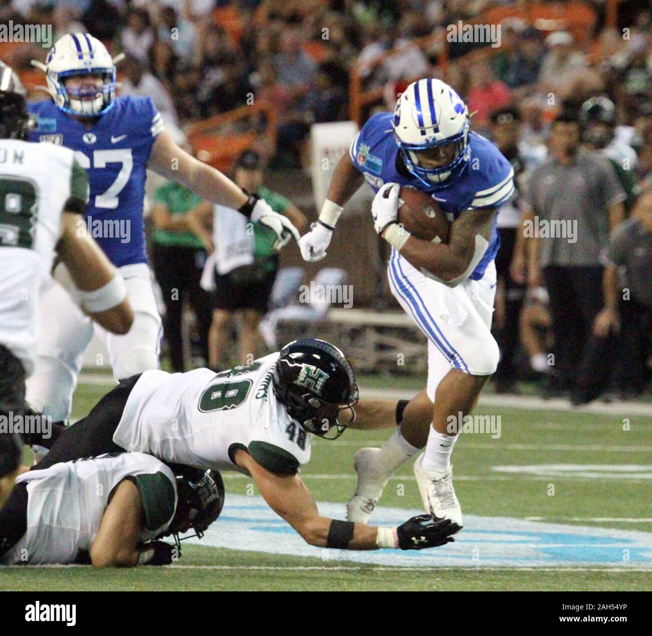 Honolulu, Hawaii, USA. Le 24 décembre, 2019. 24 décembre 2019 - les Cougars de Brigham Young de secondeur Tyler Allgeier (25) passe devant l'bras tendus d'Hawaii Rainbow Warriors joueur défensif Derek Thomas (48) au cours d'une partie à la SoFi Hawaii Bowl entre les Cougars de Brigham Young et de l'Indiana Rainbow Warriors au shérif Stan Center à Honolulu, HI - Michael Sullivan/CSM. Credit : Cal Sport Media/Alamy Live News Banque D'Images