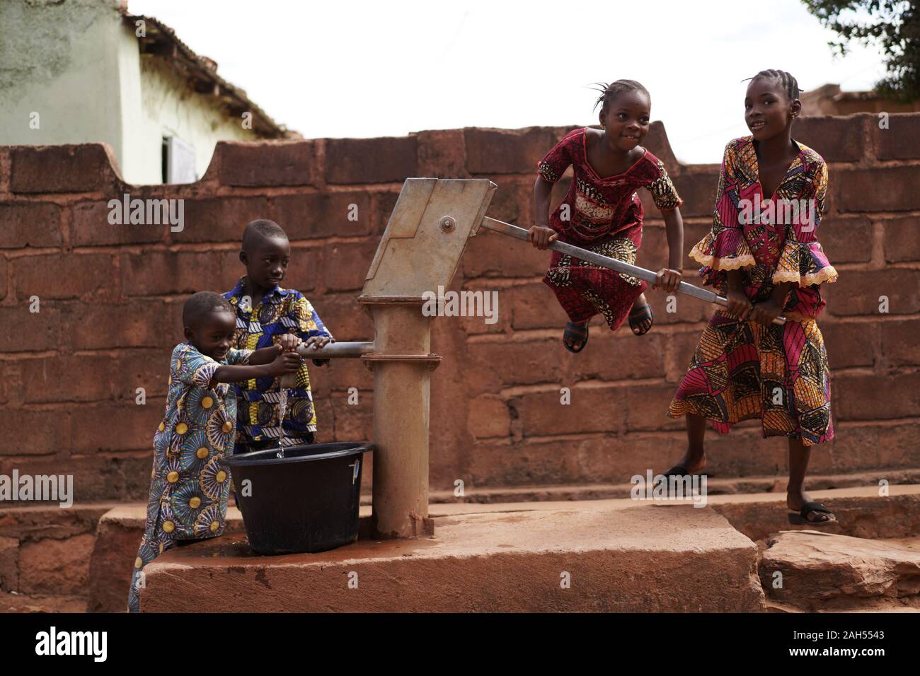 Les Enfants De L'Afrique De L'Ouest Qui Se Remplisse Un Seau D'Eau Au Borehole Banque D'Images