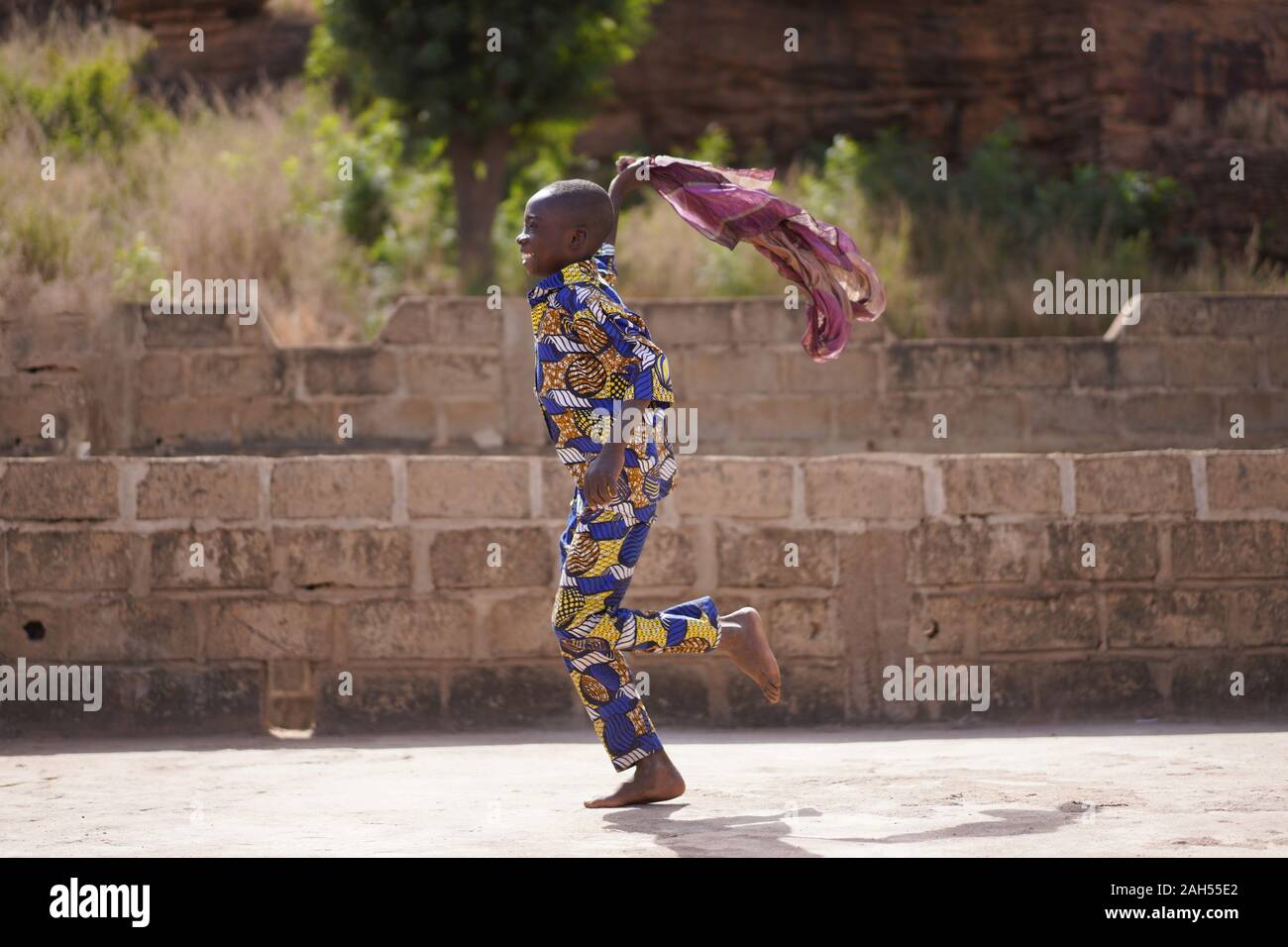 Smiling Little Boy en tenue traditionnelle africaine en plein air de jeu avec un foulard Violet Banque D'Images