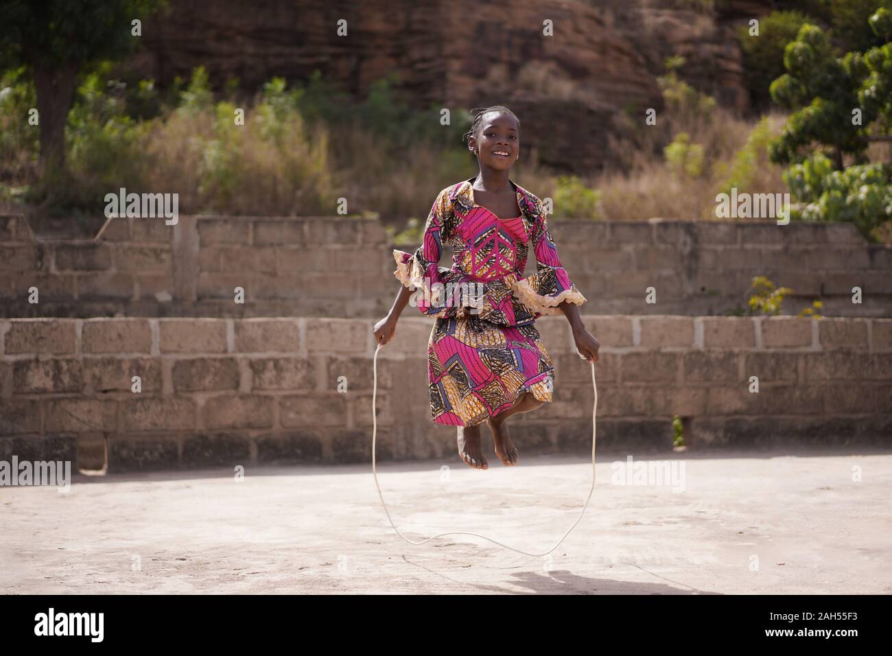 Souriante Jeune fille africaine se réchauffer avec une corde à sauter dans l'arrière-cour Banque D'Images