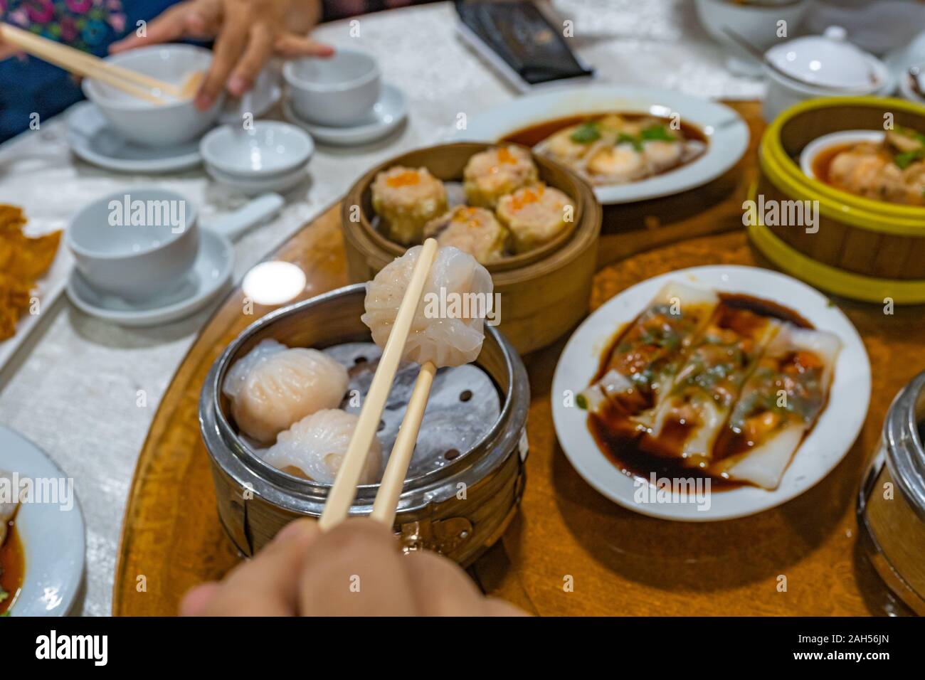 Les gens à l'aide de baguettes et avoir Hong Kong dimsum in restaurant Banque D'Images