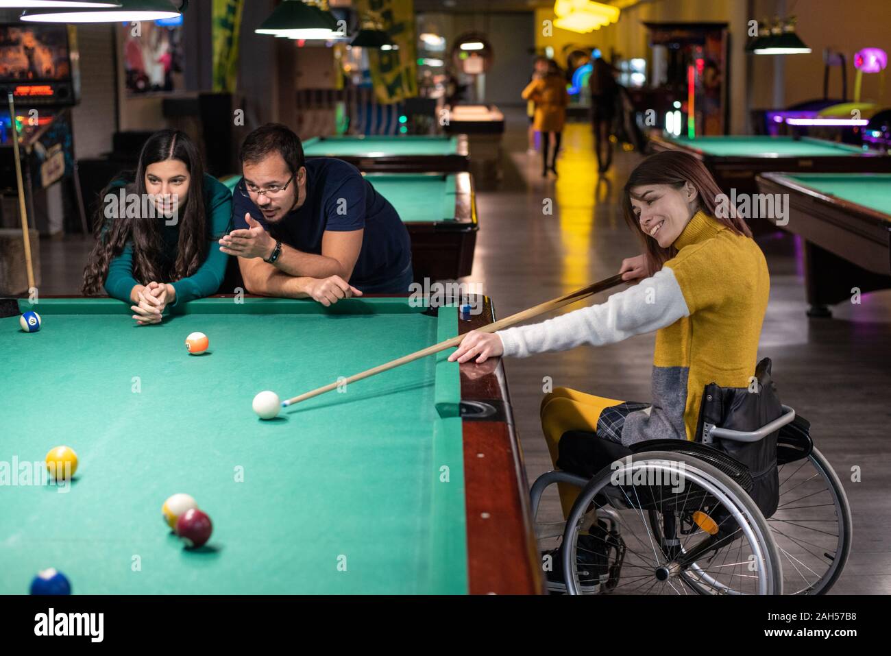 Mobilité fille dans un fauteuil roulant en jouant au billard avec des amis Banque D'Images
