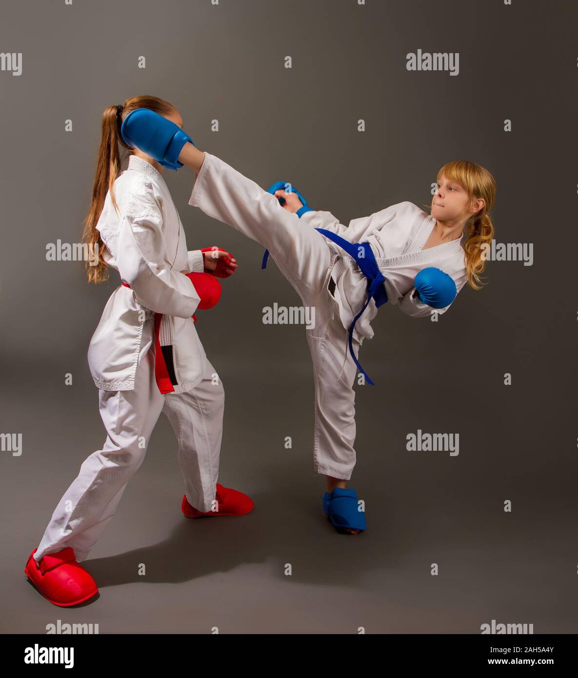 Le Karaté sportif lutte deux petites filles en kimono blanc en rouge une  seconde en kits de protection bleu Photo Stock - Alamy