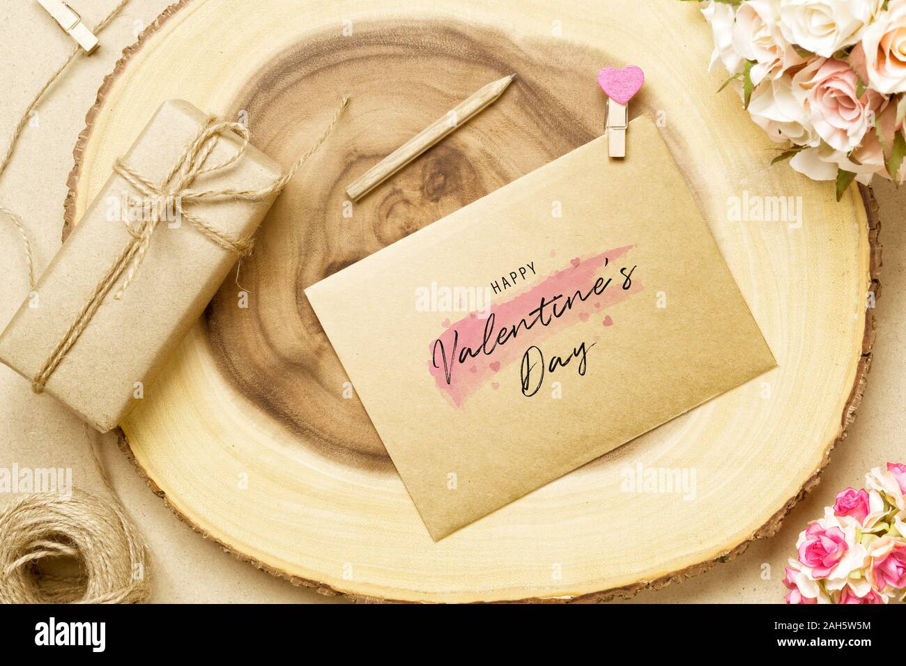 Carte postale sur l'enveloppe et la maquette bois journal avec Happy Valentine's Day text, fleur rose et boîte-cadeau. Maquette pour un design élégant. Télévision jeter dessus valen Banque D'Images
