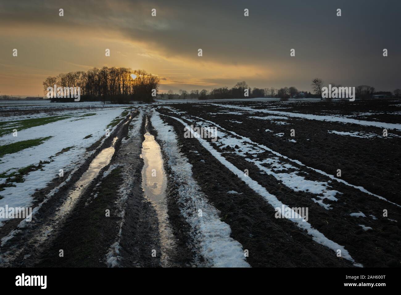Chemin de terre boueux, neige sur le terrain, cloud et le coucher du soleil Banque D'Images