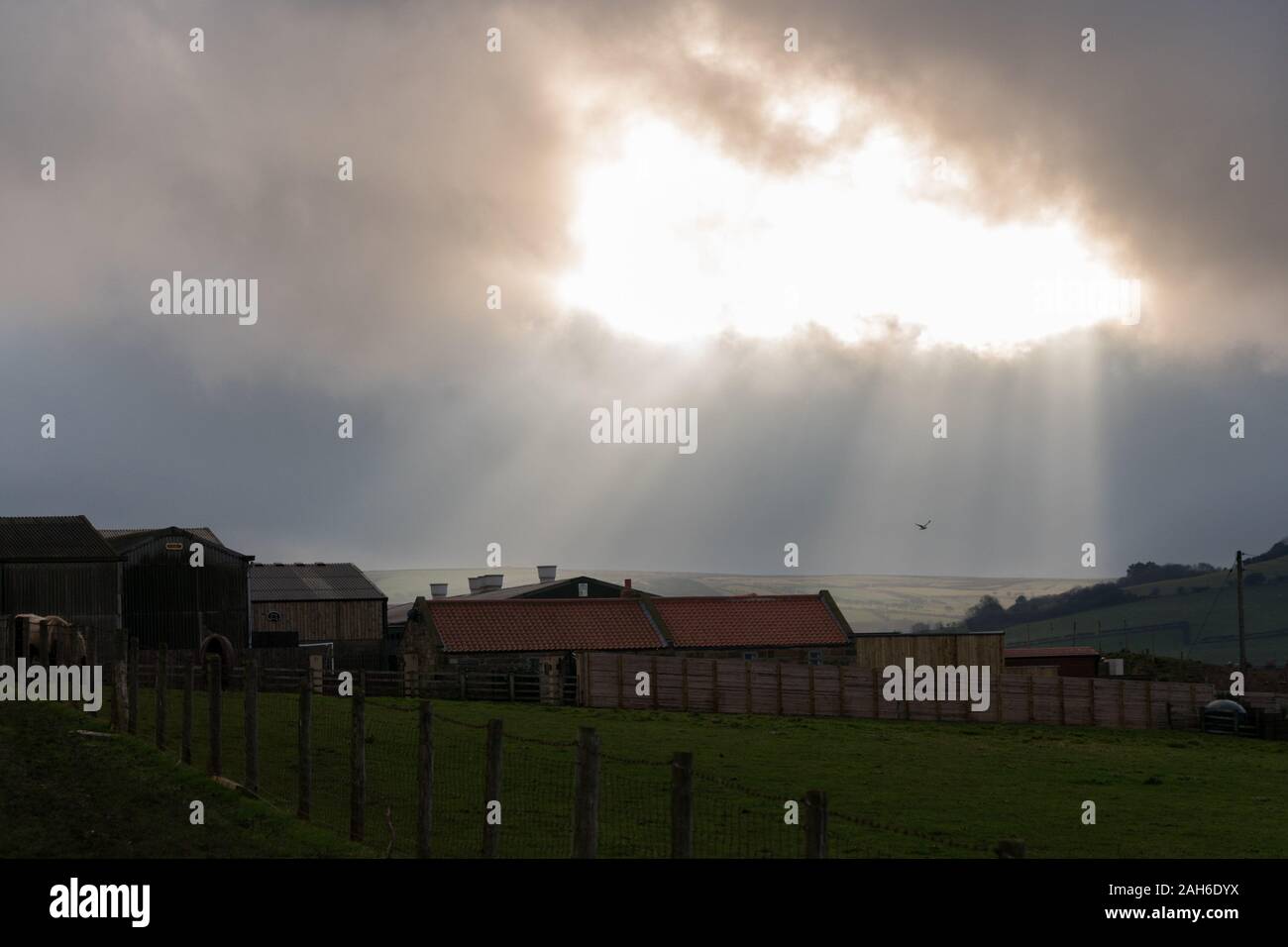La lumière du soleil éclate à partir d'une couche de nuages sur une ferme près de Staithes -village de bord de mer, dans le quartier de Scarborough, North Yorkshire, Angleterre. Banque D'Images
