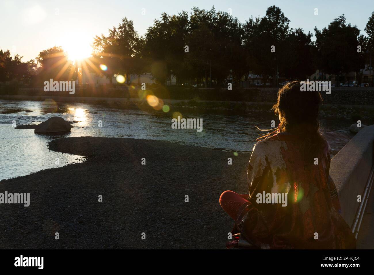 Silhouette de femme méditant sur une paroi rocheuse par la rivière Truckee au coucher du soleil Banque D'Images