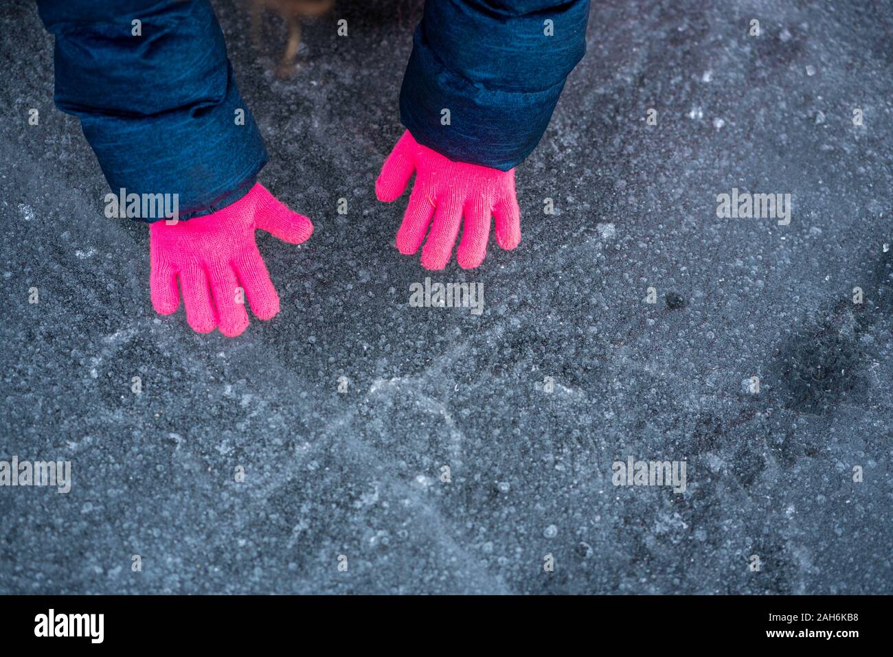 Vue aérienne de little girl wearing pink gloves sur gris-bleu glace en hiver Banque D'Images