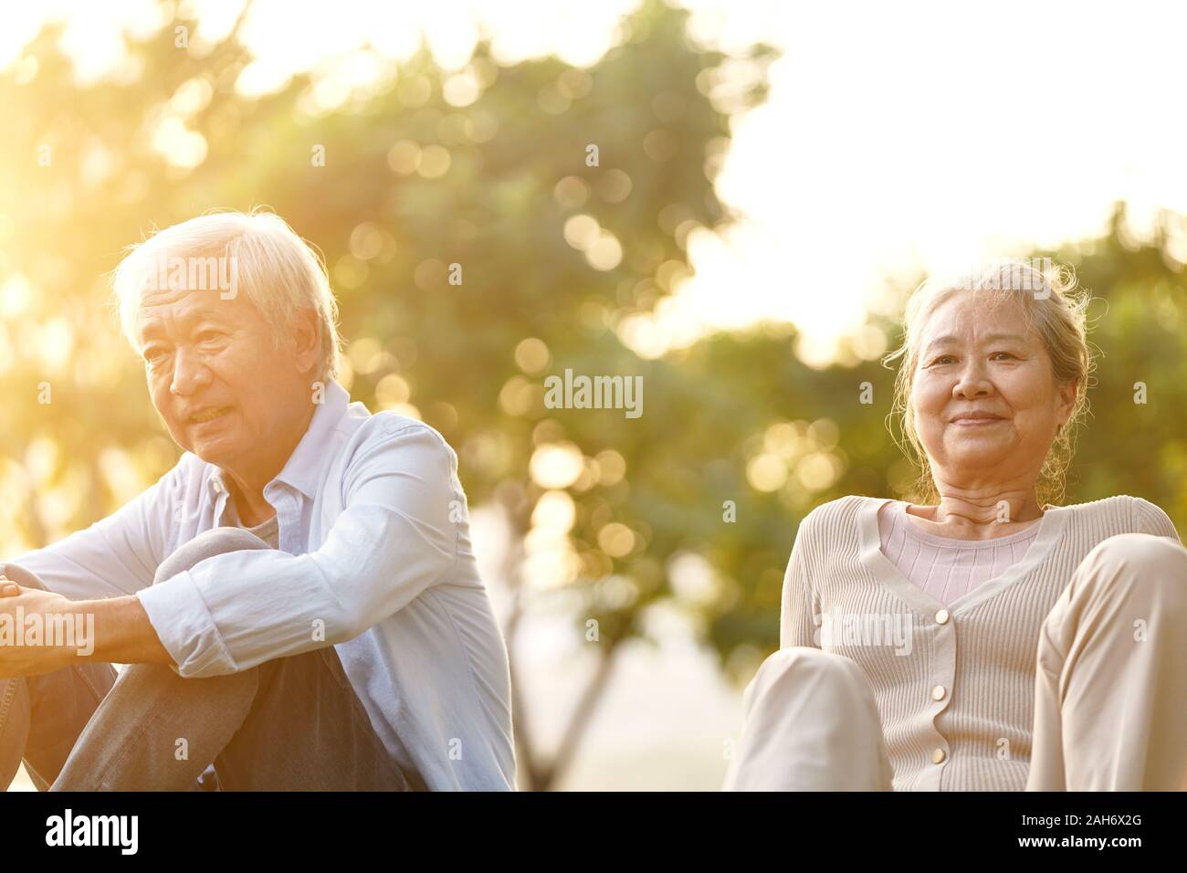 Asian senior couple sitting on grass profitant de coucher du soleil à l'extérieur dans le parc Banque D'Images