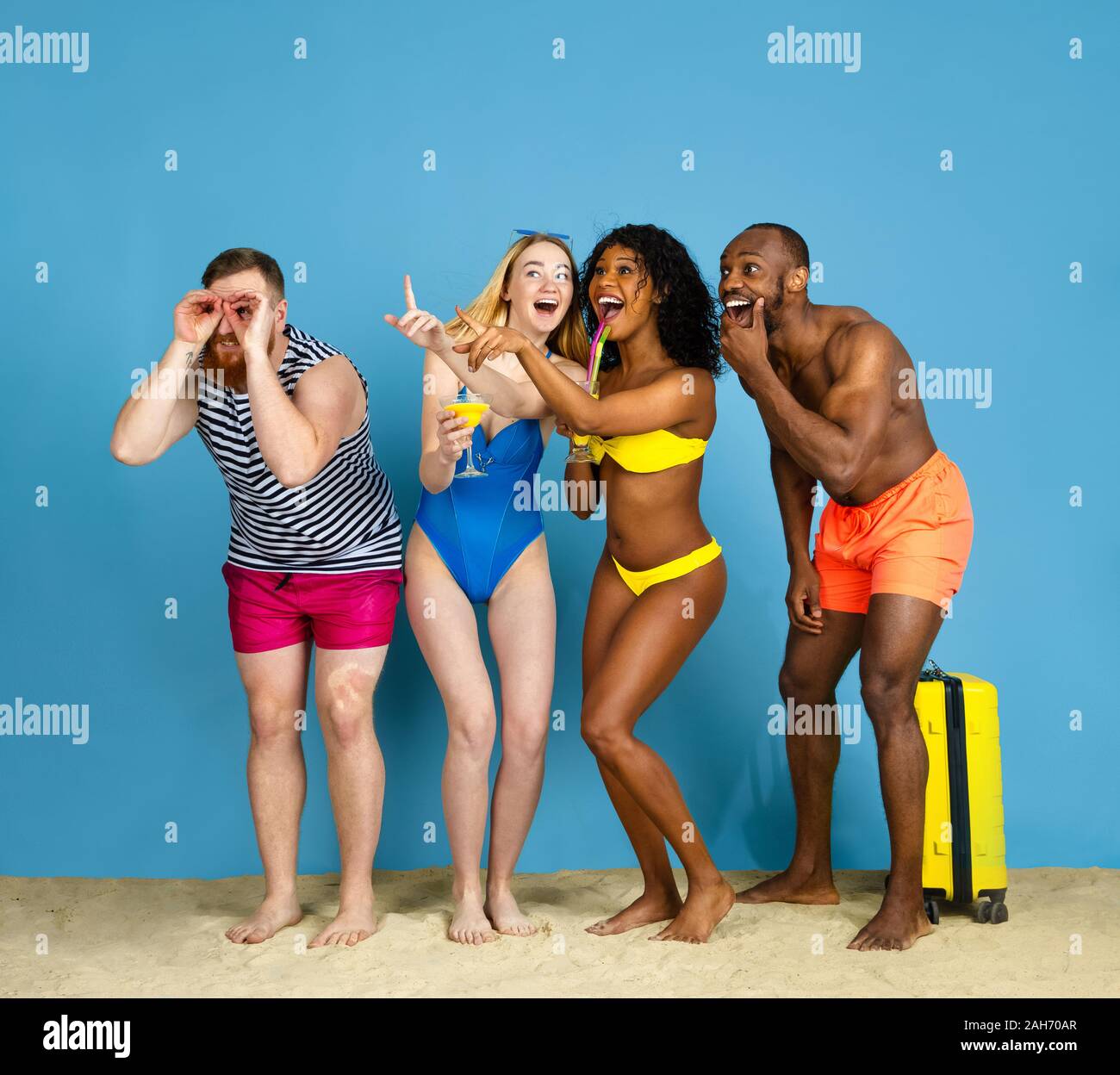 Prêts à faire la fête. Heureux les jeunes amis se reposer et s'amuser sur fond studio bleu. Concept d'émotions humaines, expression du visage, vacances d'été ou de fin de semaine. Chill, été, mer, océan. Banque D'Images