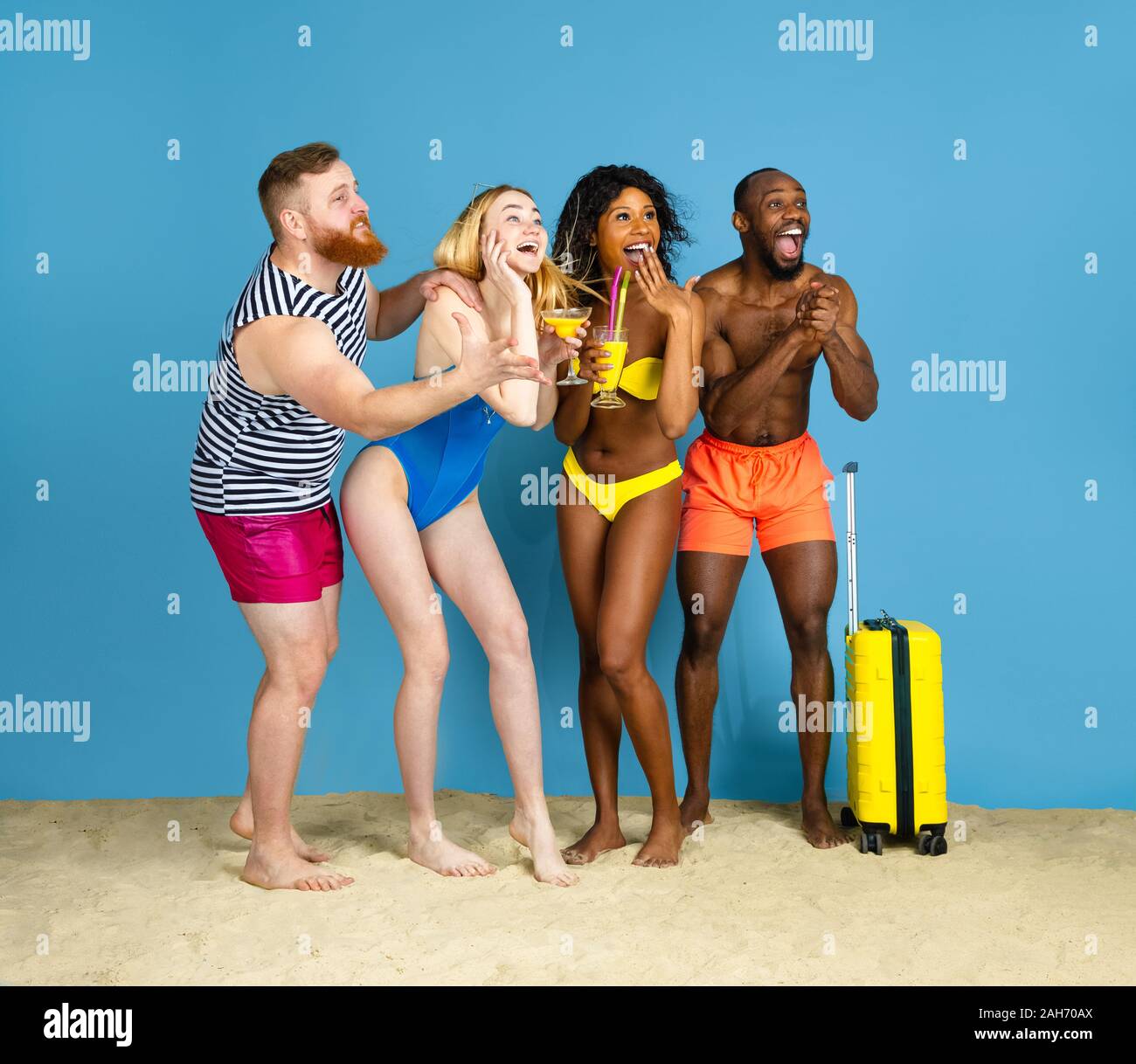 Prêts à faire la fête. Heureux les jeunes amis se reposer et s'amuser sur fond studio bleu. Concept d'émotions humaines, expression du visage, vacances d'été ou de fin de semaine. Chill, été, mer, océan. Banque D'Images