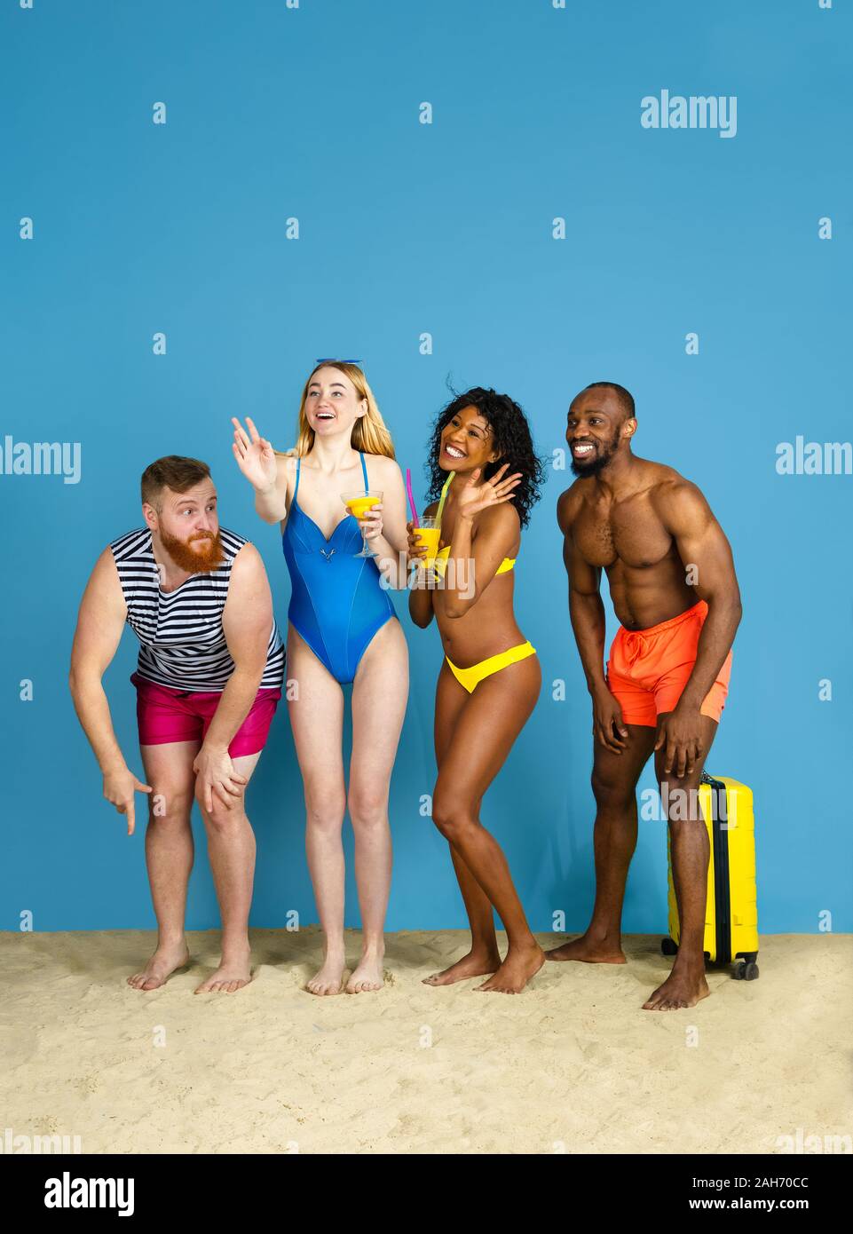 Prêts à faire la fête. Heureux les jeunes amis se reposer et s'amuser sur fond studio bleu. Concept d'émotions humaines, expression du visage, vacances d'été ou de fin de semaine. Chill, été, mer, océan. Banque D'Images