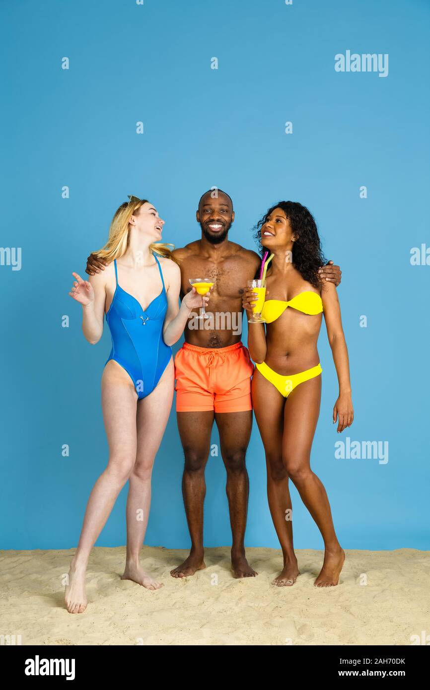 Prêts à faire la fête. Heureux les jeunes amis se reposer et s'amuser sur fond studio bleu. Concept d'émotions humaines, expression du visage, vacances d'été ou de fin de semaine. Chill, été, mer, océan. Banque D'Images