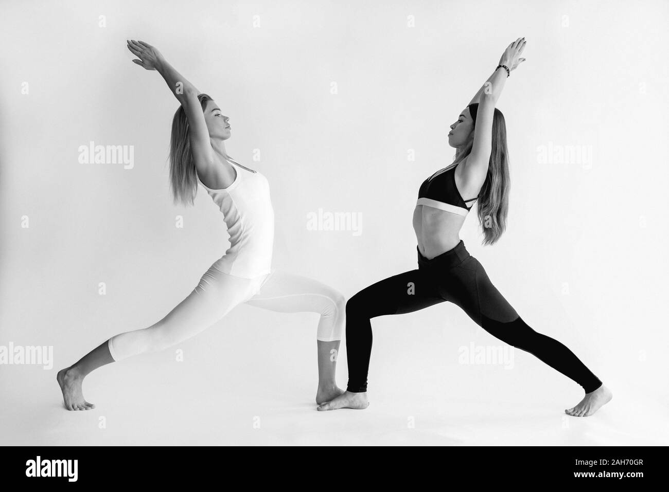 Portrait monochrome de blonde and brunette belle femme gaie faisant des asanas de yoga. Mode de vie sain, Yin et Yang et sport concept Banque D'Images