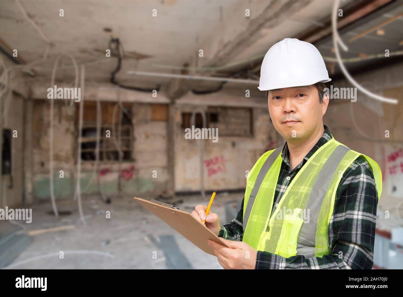 Un travailleur asiatique d'âge moyen contrôler quelque chose avec une liste à la main. Banque D'Images