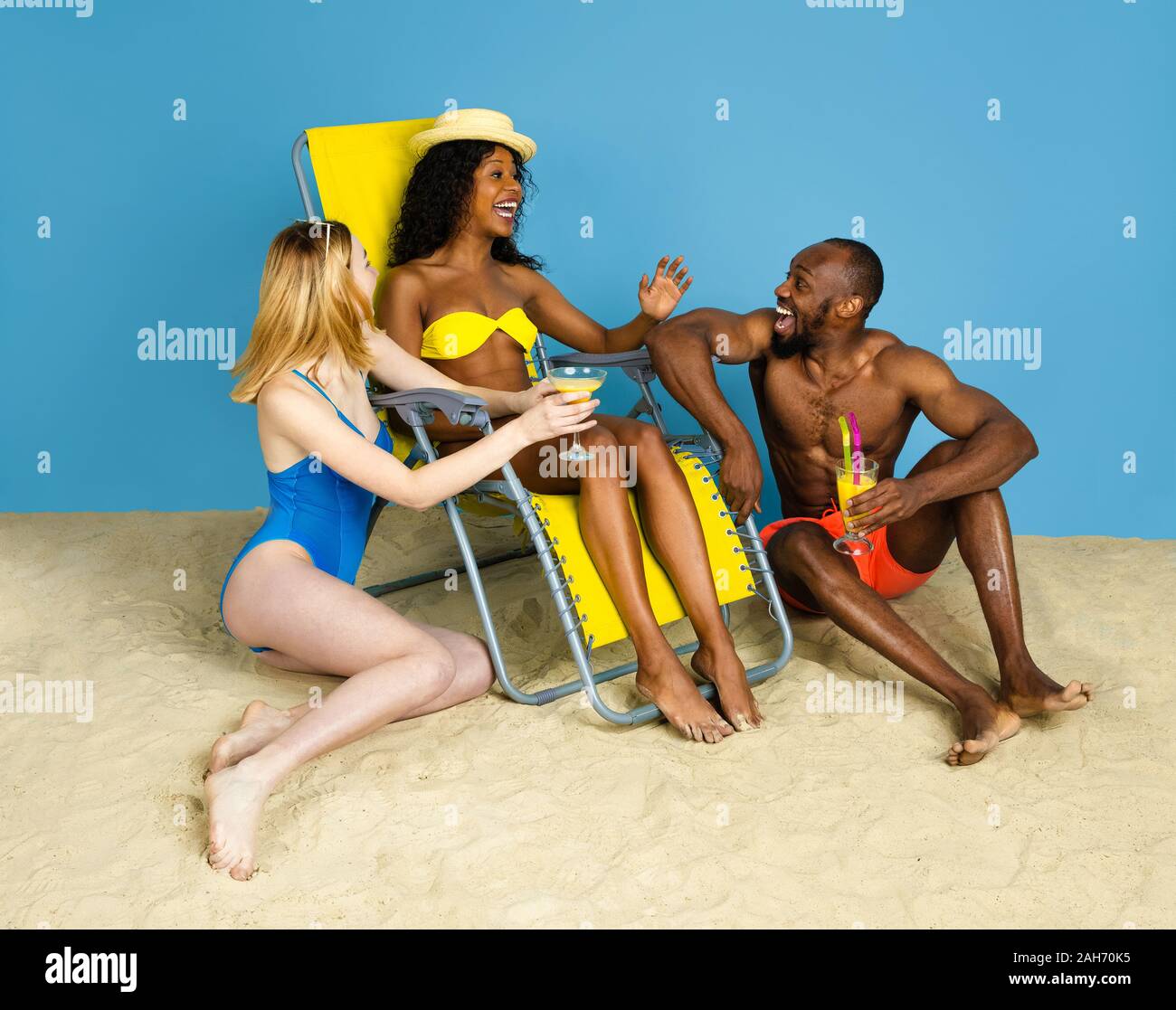 Histoire d'été. Heureux les jeunes amis se reposer et s'amuser sur fond studio bleu. Concept d'émotions humaines, expression du visage, vacances d'été ou de fin de semaine. Chill, été, mer, océan. Banque D'Images