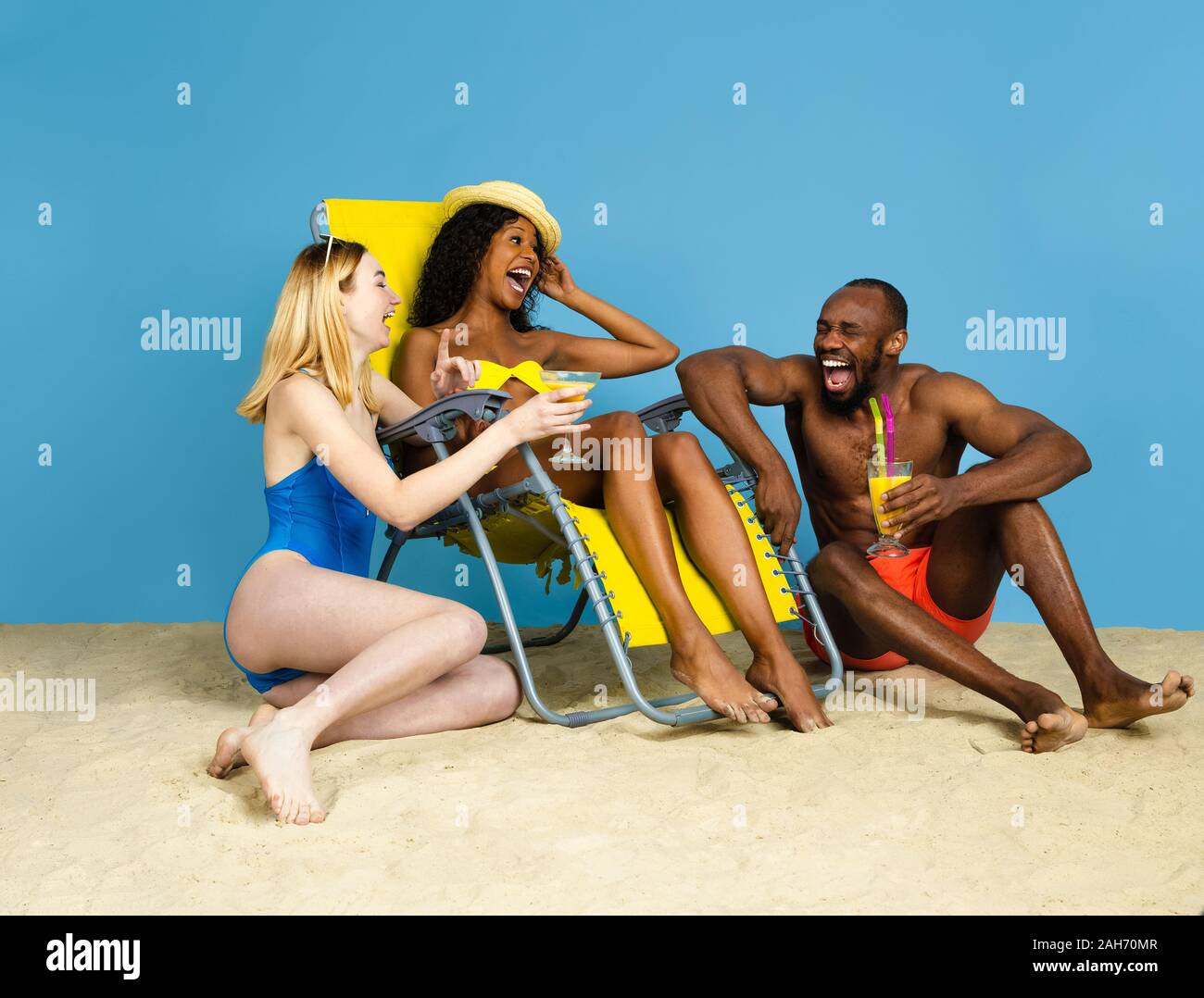 Histoire d'été. Heureux les jeunes amis se reposer et s'amuser sur fond studio bleu. Concept d'émotions humaines, expression du visage, vacances d'été ou de fin de semaine. Chill, été, mer, océan. Banque D'Images