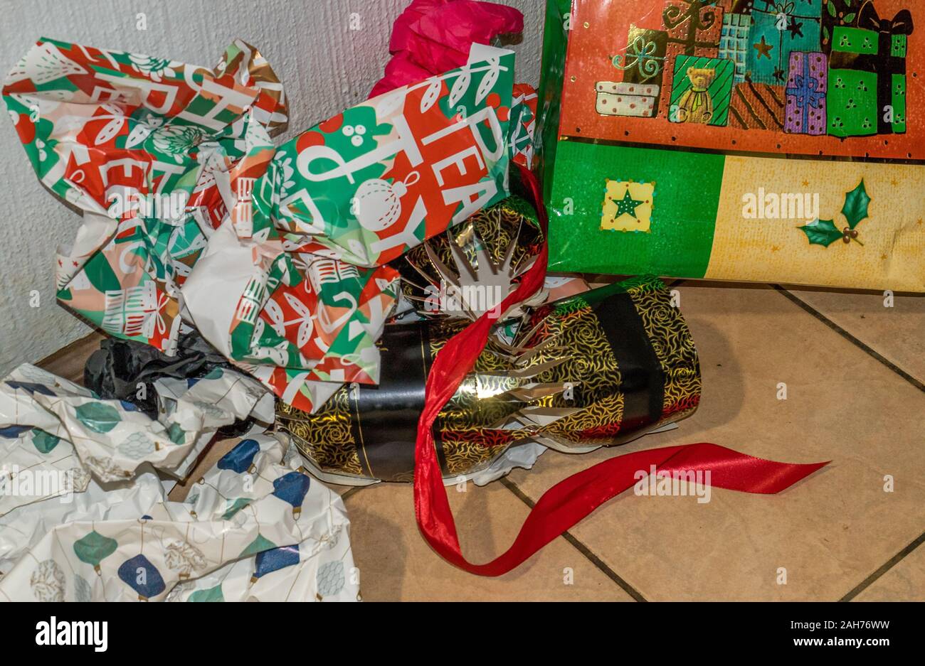Emballages cadeaux de Noël utilisés se situent dans un tas sur le sol après l'ouverture de l'image présente en format horizontal Banque D'Images