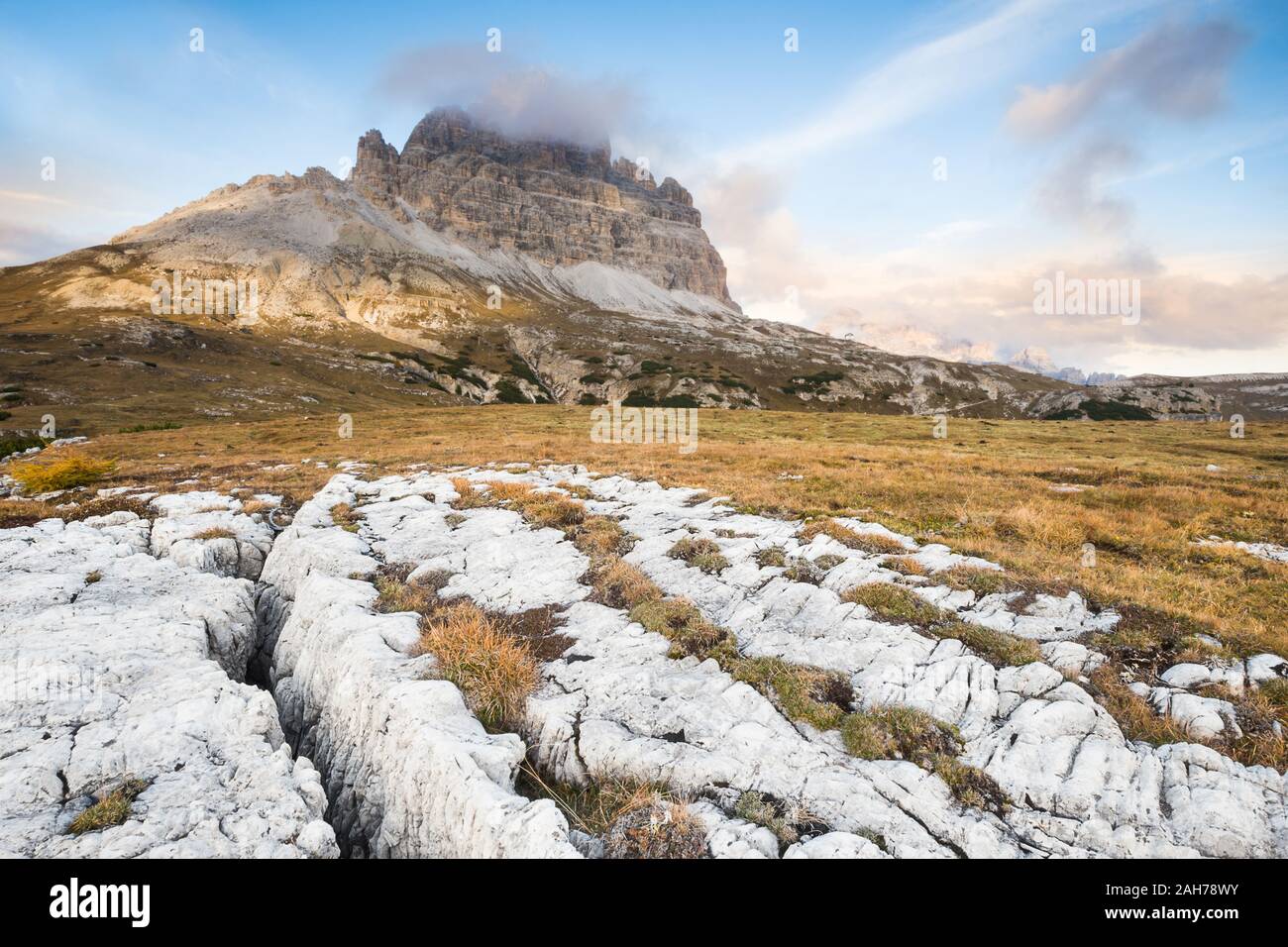 Vue grand angle au coucher du soleil sur les trois sommets de Lavaredo, avec des rochers blancs au premier plan, sous un ciel bleu d'été avec des nuages puffy Banque D'Images