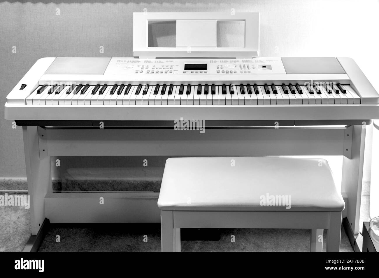 Piano électronique numérique blanc sur le stand avec une chaise et un porte-livre musique - instruments de musique synthétiseur Banque D'Images