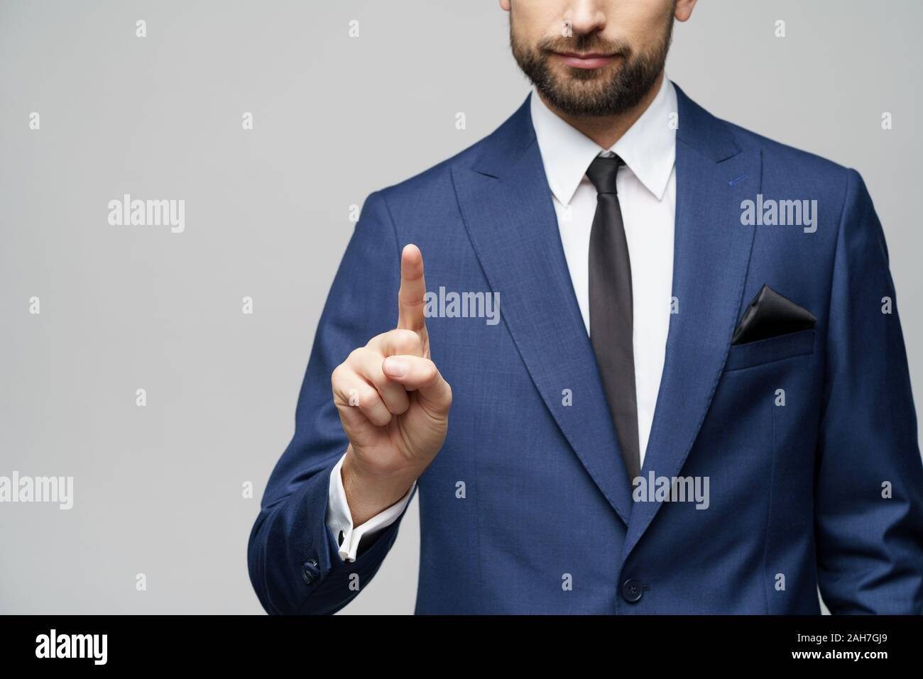 Businessman pointer du doigt, poussant la main invisible de l'écran écran tactile, l'homme d'affaires numérique en appuyant sur le bouton virtuel sur fond gris isolé Banque D'Images