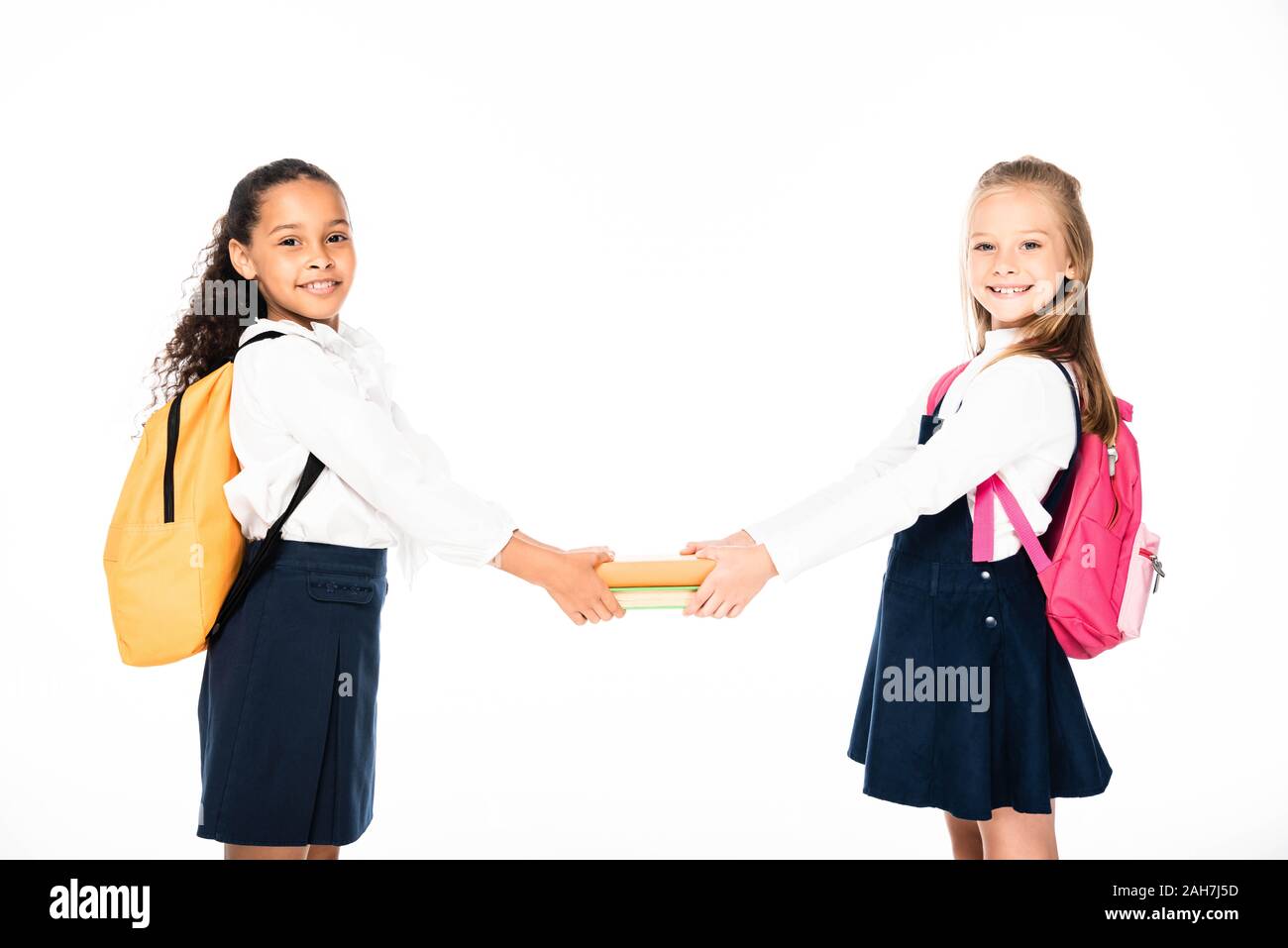 Deux écolières multiculturelle joyeuse holding books ensemble isolated on white Banque D'Images
