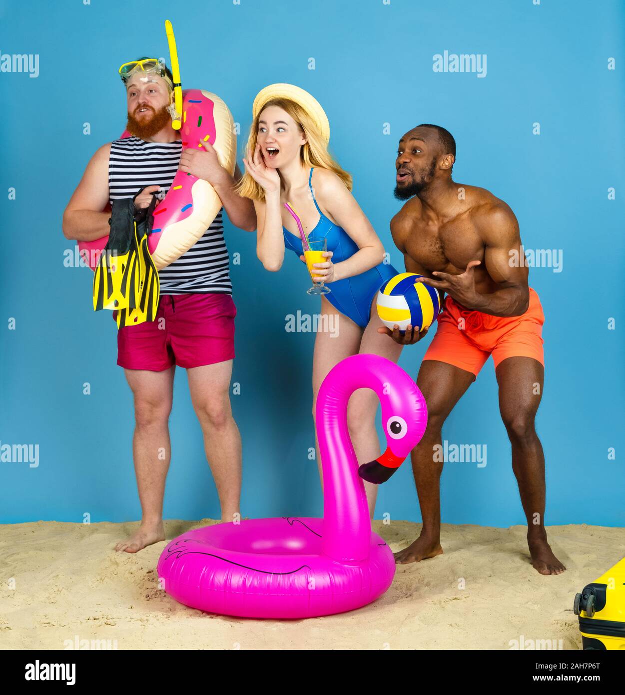 Préparé pour le voyage. Heureux les jeunes amis se reposer et regarder étonné sur fond studio bleu. Concept d'émotions humaines, expression du visage, vacances d'été ou de fin de semaine. Chill, été, mer, océan. Banque D'Images