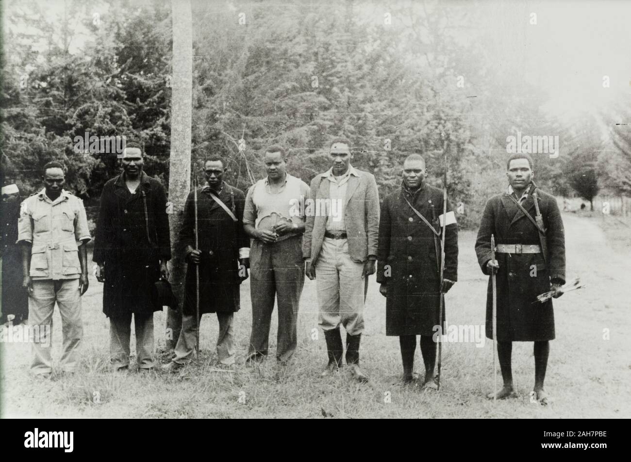 Au Kenya, les membres d'un comité d'settler's Home Guard holding lances et d'arcs et flèches. Certains grands manteaux militaire, peut-être un vestige de service dans la King's African Rifles pendant la Seconde Guerre mondiale. Légende:Le manuscrit original 'Home Guard' mis en place et formé par un agriculteur pour la protection de sa maison. Armés de lances et d'arcs et flèches, 1953. 1995/076/1/1/15/2.25. Banque D'Images