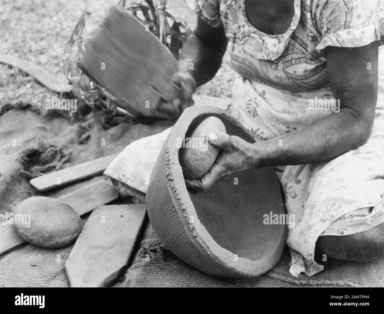Fidji, faire un pot en argile, FijiA femme agenouillée façonne un pot en argile à l'aide d'une pierre arrondie et une palette de bois. Sous-titre suivant : poteries faites à la main, 1965. 2005/010/1/14/92. Banque D'Images