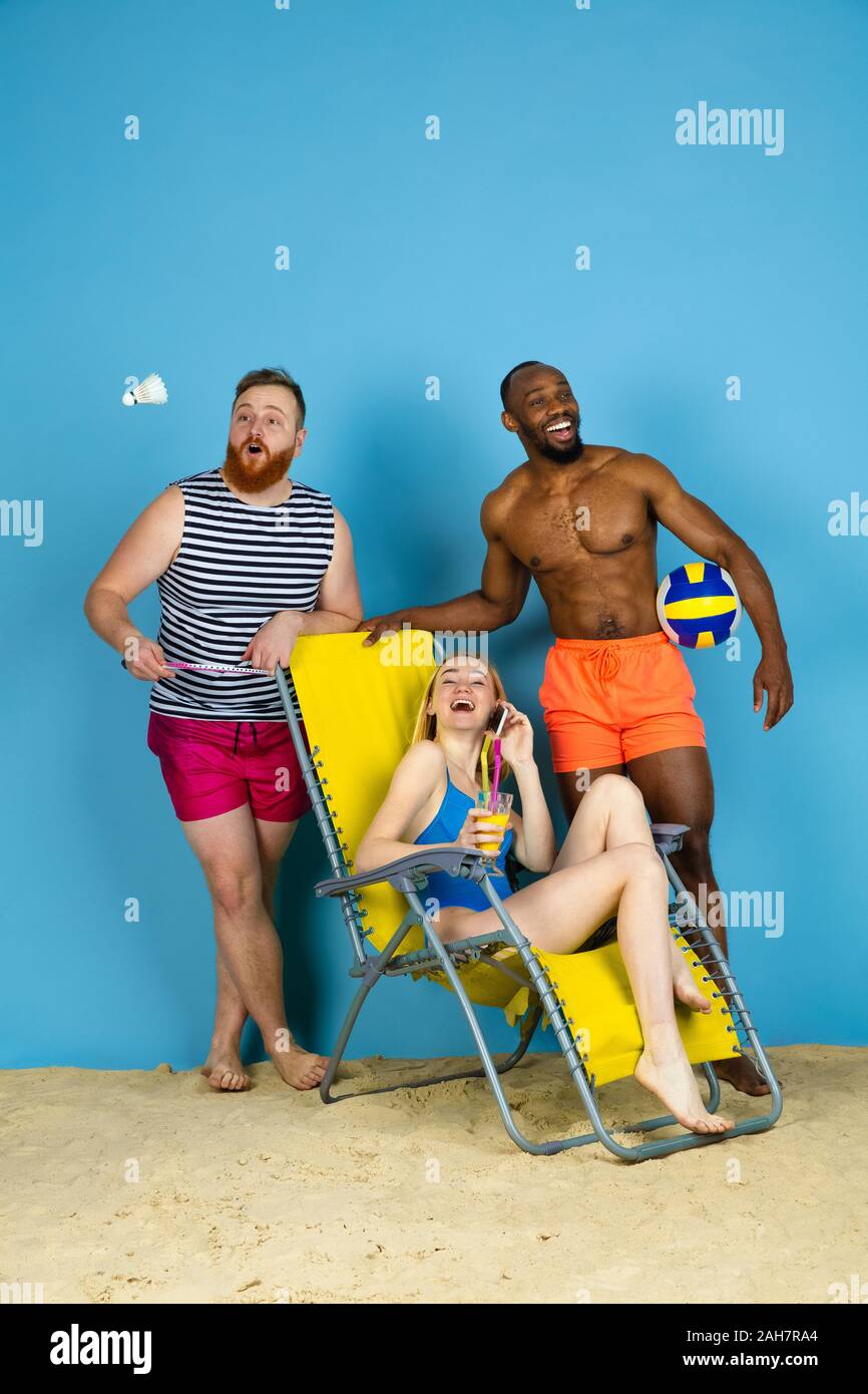 Temps pour l'activité. Happy friends resting et jouant sur fond studio bleu. Concept d'émotions humaines, expression du visage, vacances d'été ou de fin de semaine. Chill, été, mer, océan. Banque D'Images