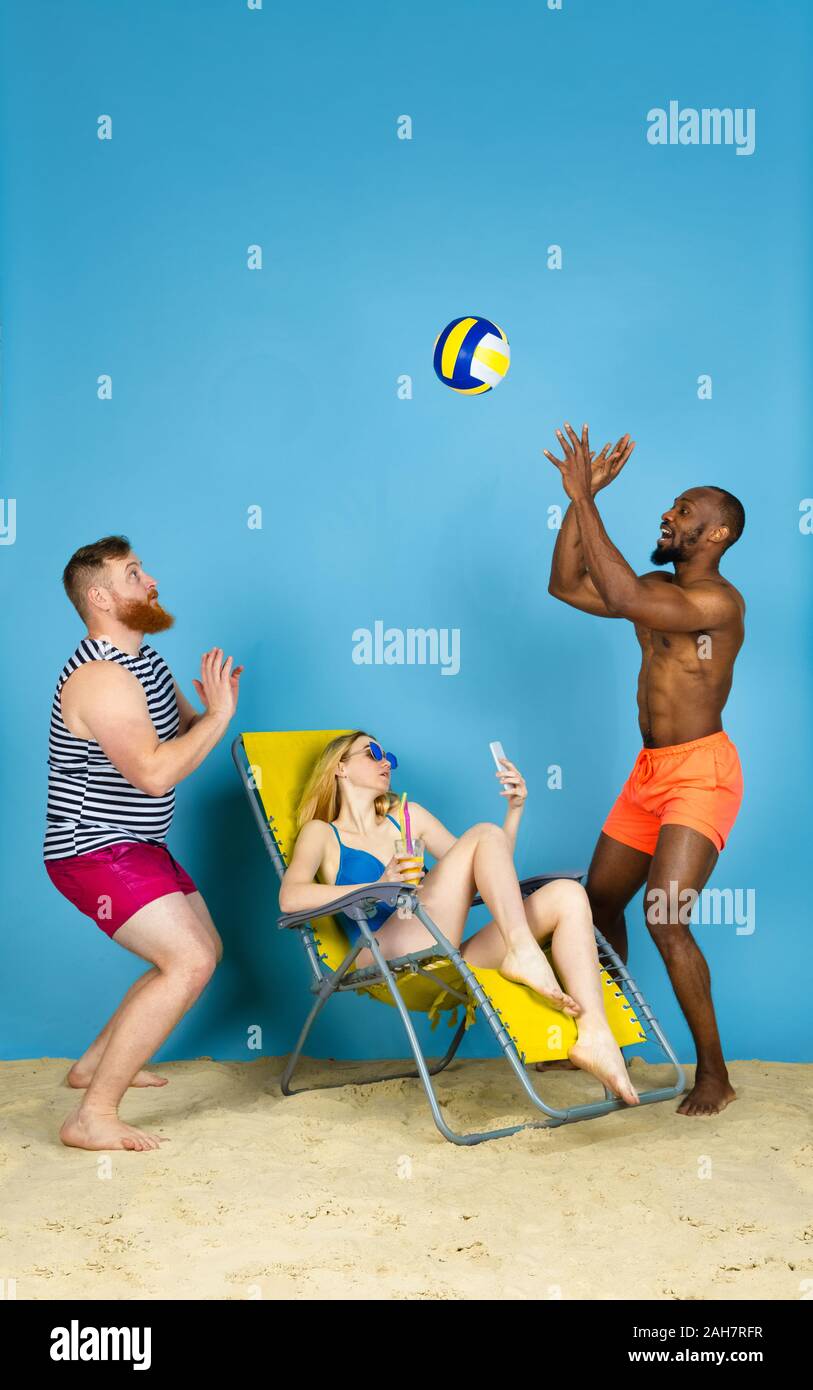 Temps pour l'activité. Happy friends prendre, jouer au volley-ball selfies bleu sur fond de studio. Concept d'émotions humaines, expression du visage, vacances d'été ou de fin de semaine. Chill, été, mer, océan. Banque D'Images