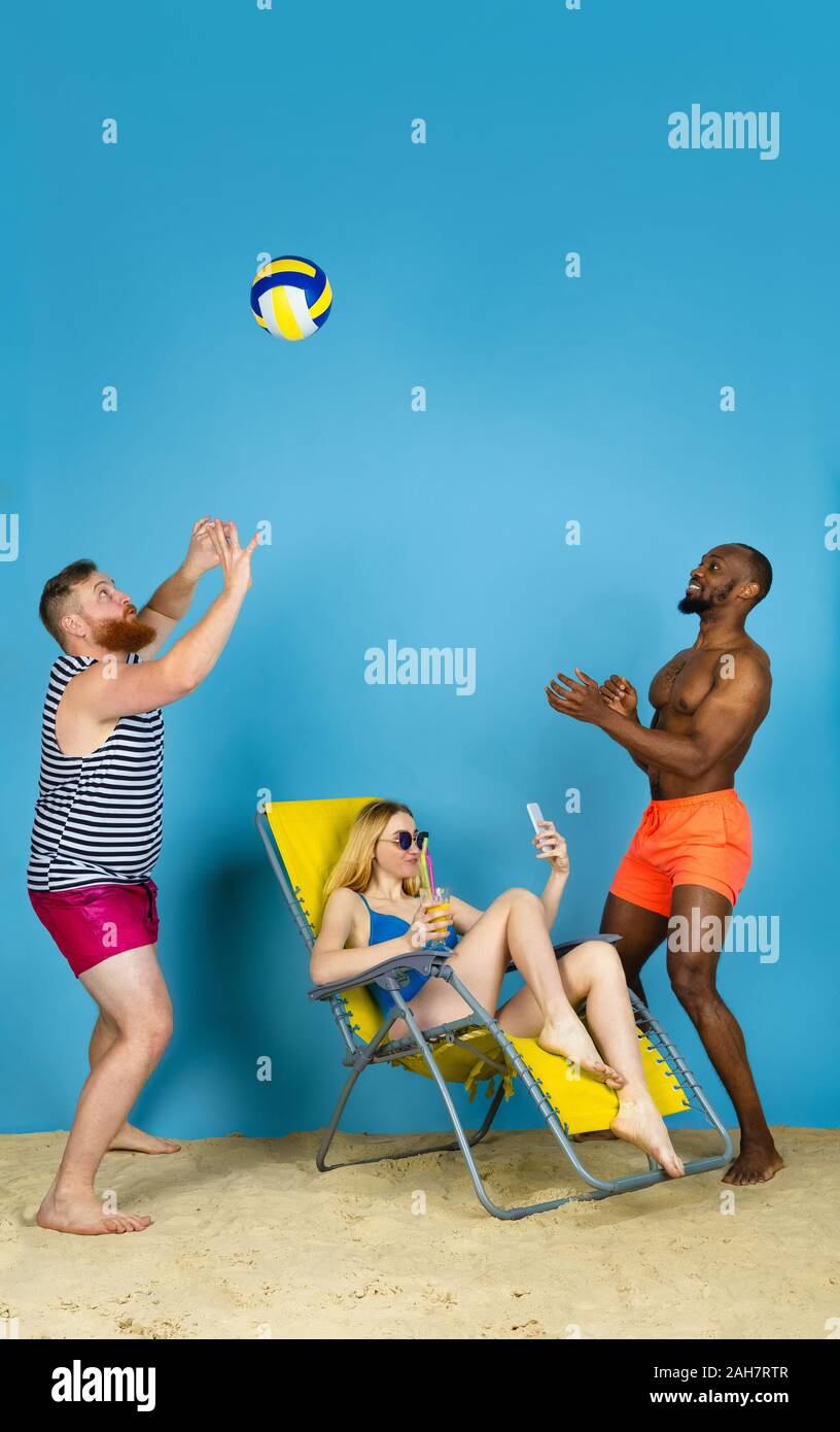Temps pour l'activité. Happy friends prendre, jouer au volley-ball selfies bleu sur fond de studio. Concept d'émotions humaines, expression du visage, vacances d'été ou de fin de semaine. Chill, été, mer, océan. Banque D'Images