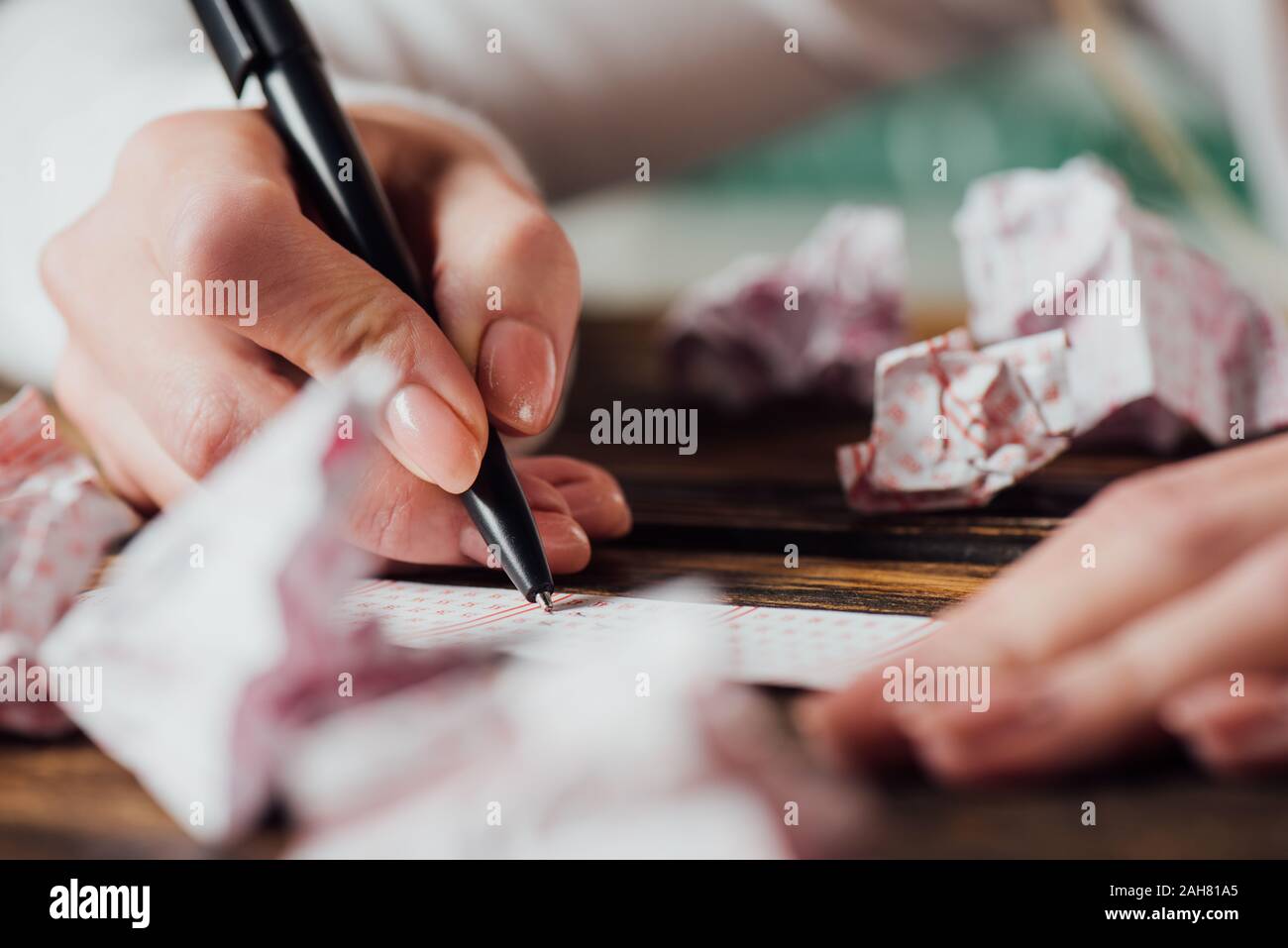 Portrait de joueur marquant les nombres dans près de billet de loterie loterie froissé cartes sur table en bois Banque D'Images