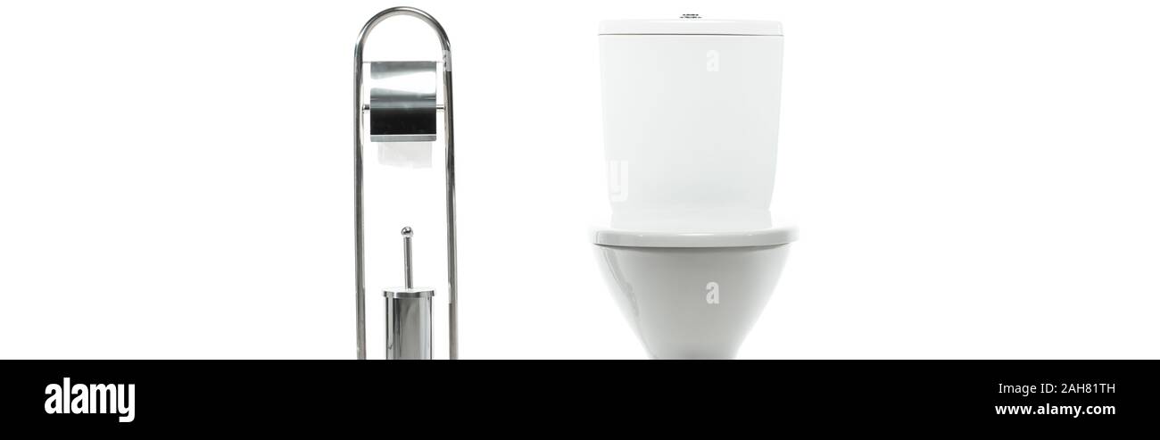 Nettoyer la cuvette des toilettes en céramique près de support métallique avec du papier toilette et brosse isolé sur blanc, vue panoramique tourné Banque D'Images