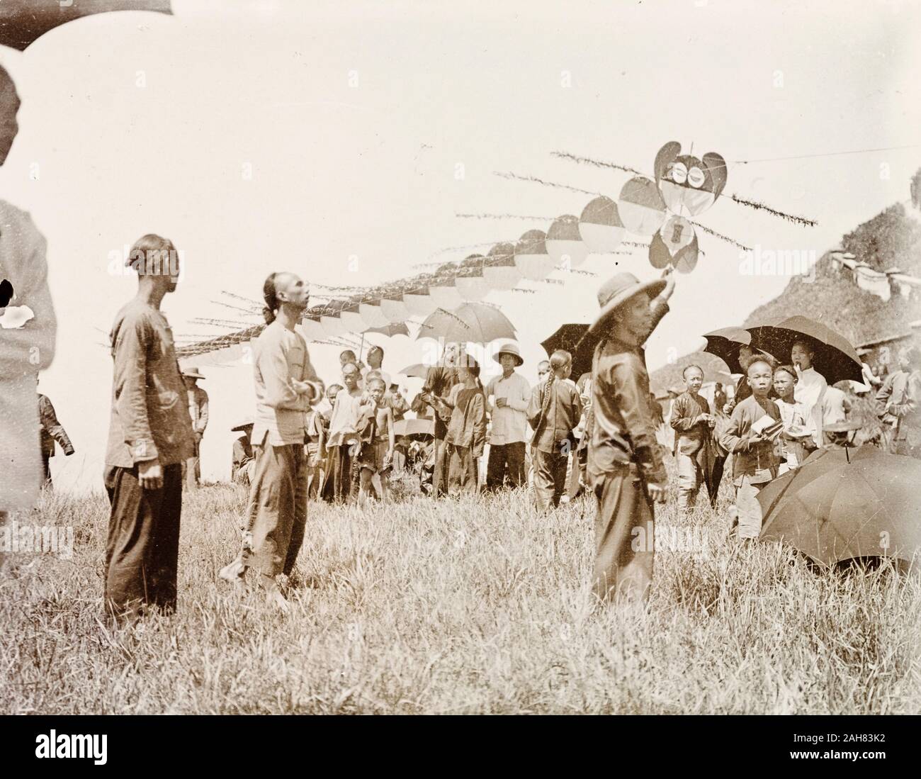 La Chine, un cerf-volant, construit dans les segments pour ressembler à un dragon, est prêt à voler. Un groupe de spectateurs se rassemblent pour surveiller, à l'abri du soleil sous des parasols.manuscrit original description : Dragon cerf-volant, vers 1905. 1998/028/1/1/23. Banque D'Images