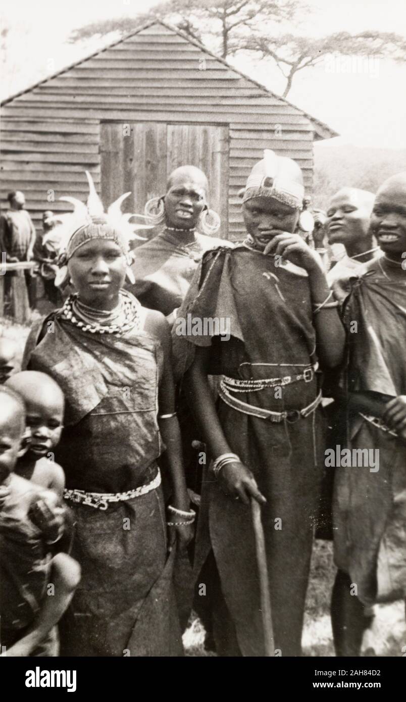 Au Kenya, un groupe de femmes en costume traditionnel avec des bijoux et des coiffures, accompagnés de leurs enfants à un type d'événement en plein air, 1933-1934. 1995/076/1/1/22/12. Banque D'Images