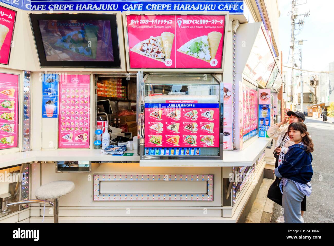 Deux jeunes femmes japonaises à emporter le choix de crêpes de l'extérieur du menu au Café Crêperie Harajuku Laforet Strawberry house à Tokyo. Banque D'Images