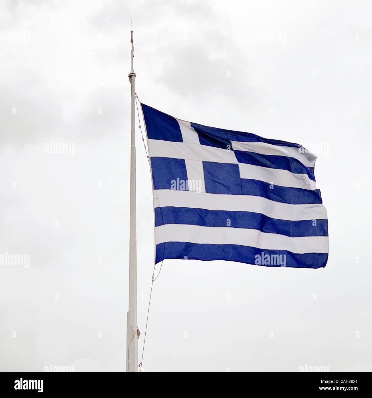 Le drapeau national de la Grèce est en forme sur un mât en cas de tempête. Appelé aussi le bleu ciel et blanc. Morceau de tissu et de bannière, utilisé comme symbole. Banque D'Images