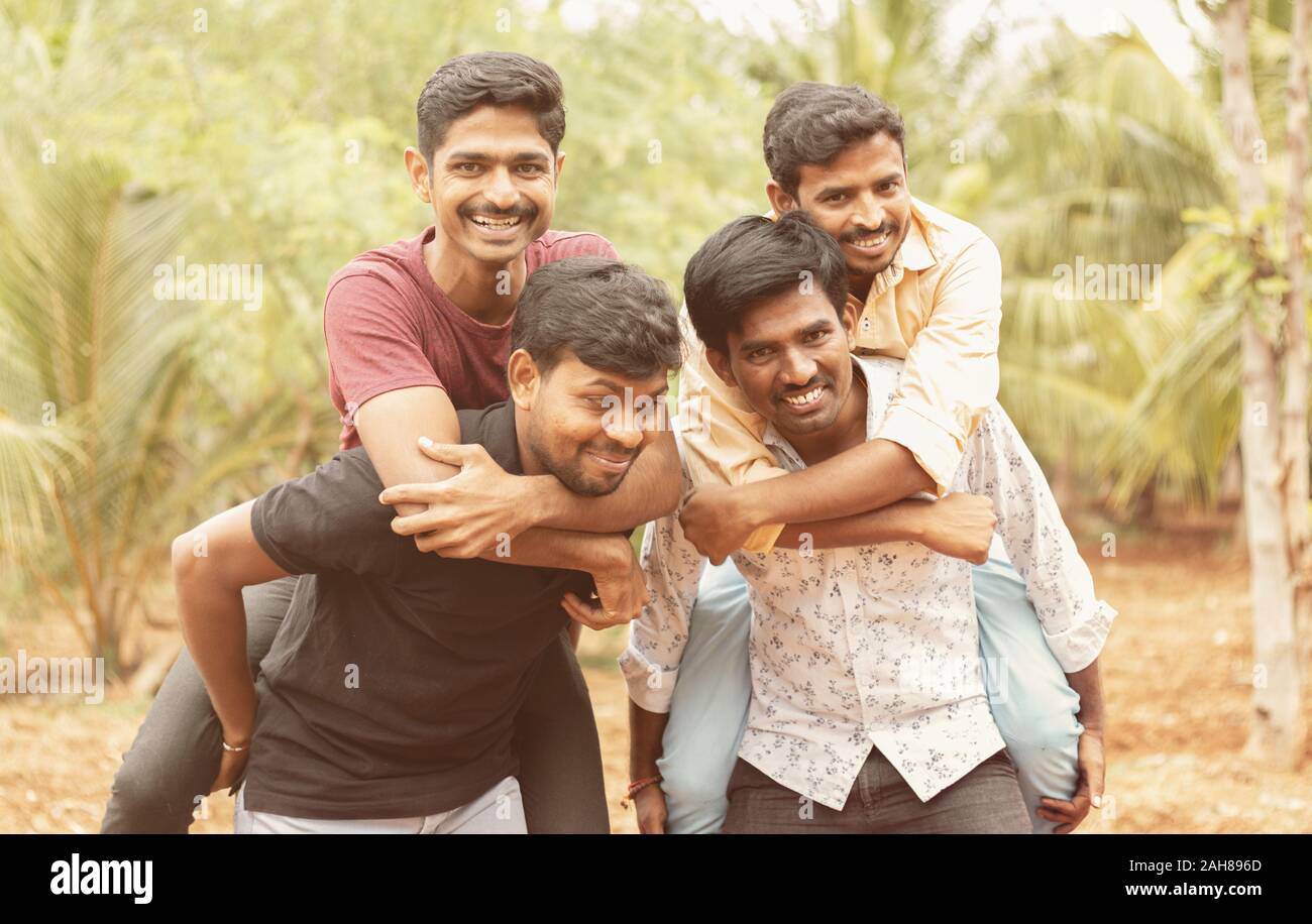 Meilleurs amis masculins Piggyback - Groupe d'amis s'amuser ensemble en plein air - Cheerful young male friends enjoying temps ensemble. Banque D'Images