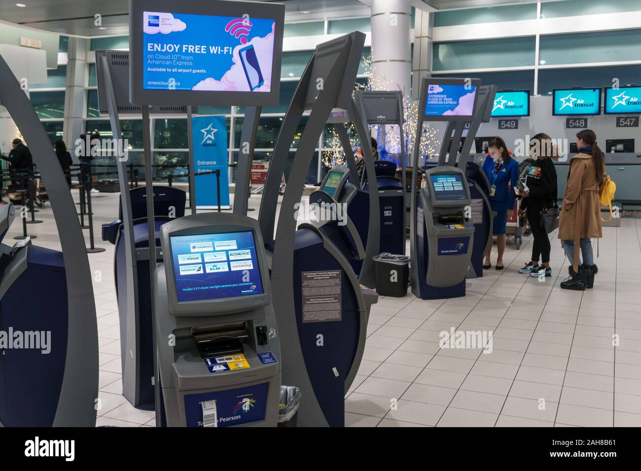 Lester Pearson Airport Zone d'enregistrement, Toronto, décembre 2019 - Les passagers de l'aide à l'enregistrement automatique dans les kiosques par un employé de la compagnie aérienne Banque D'Images