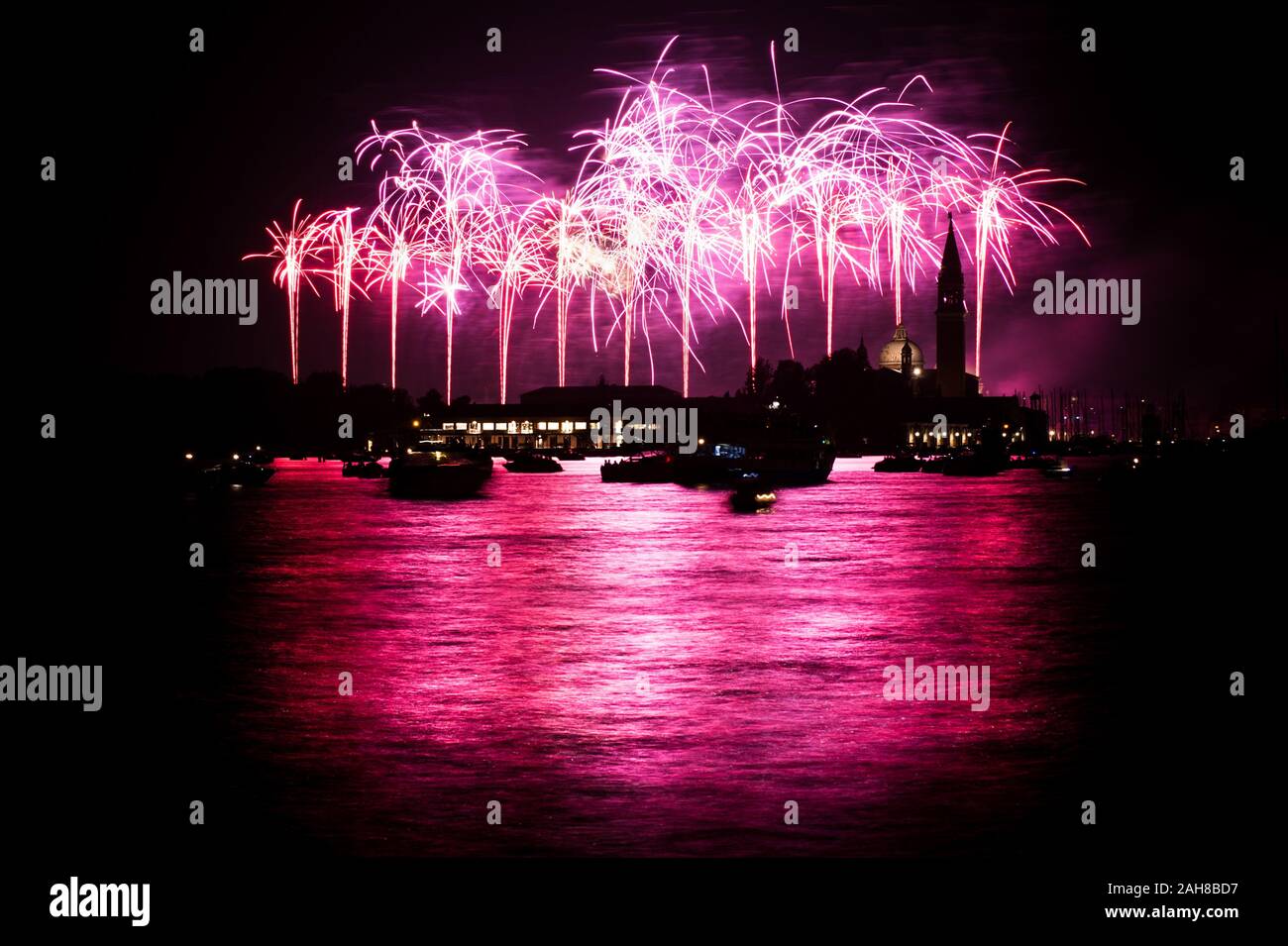 Photo nocturne emblématique de Venise, dont la silhouette est éclairée par des feux d'artifice roses Banque D'Images