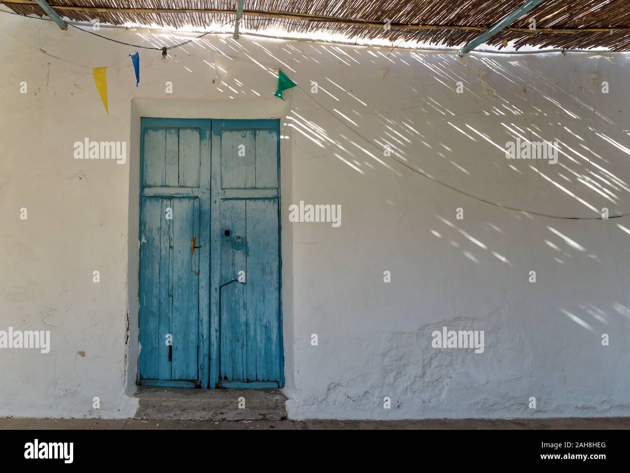 Porte en bois bleu et toit de paille, avec des rayons de lumière et ombre à abadoned église Ermita de Sant Antoni et Sant Jaume à capuchon, Altea, Spai Banque D'Images