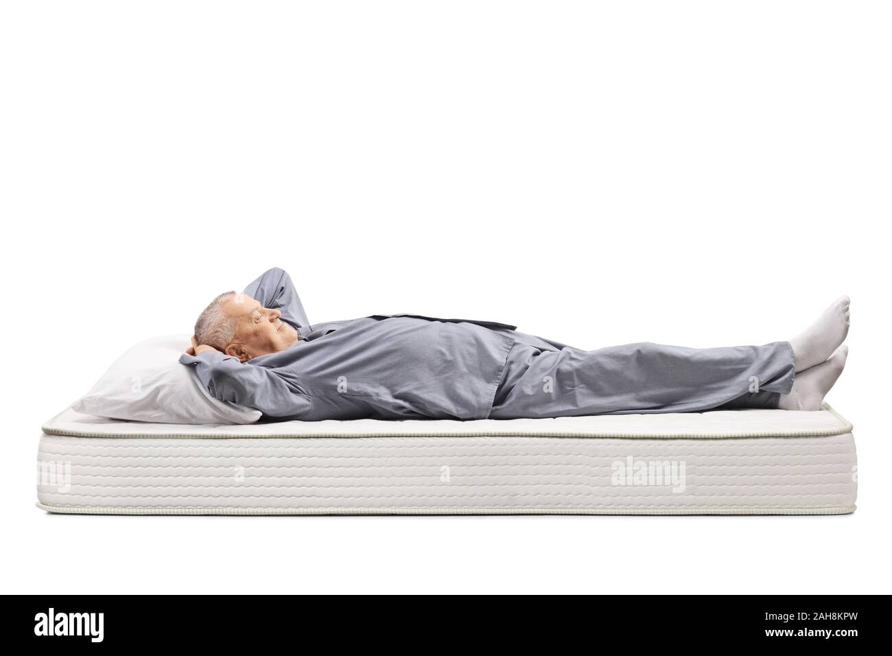 Homme mûr en pyjama allongé sur un matelas isolé sur fond blanc Banque D'Images
