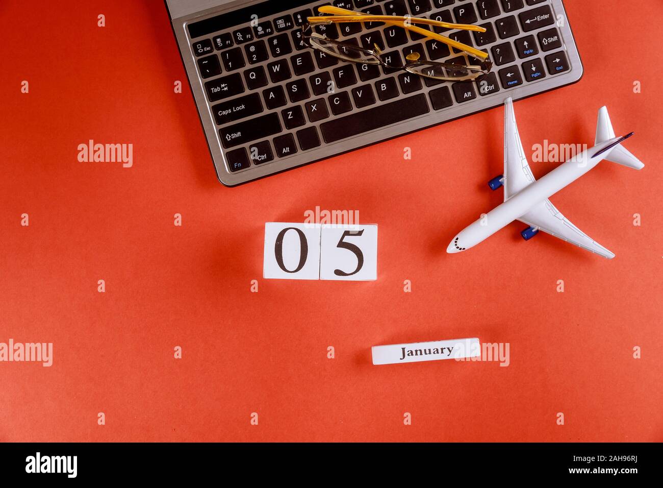 05 janvier calendrier avec le nom d'accessoires de bureau espace de travail sur clavier d'ordinateur, avion, verres sur fond rouge 24 Banque D'Images