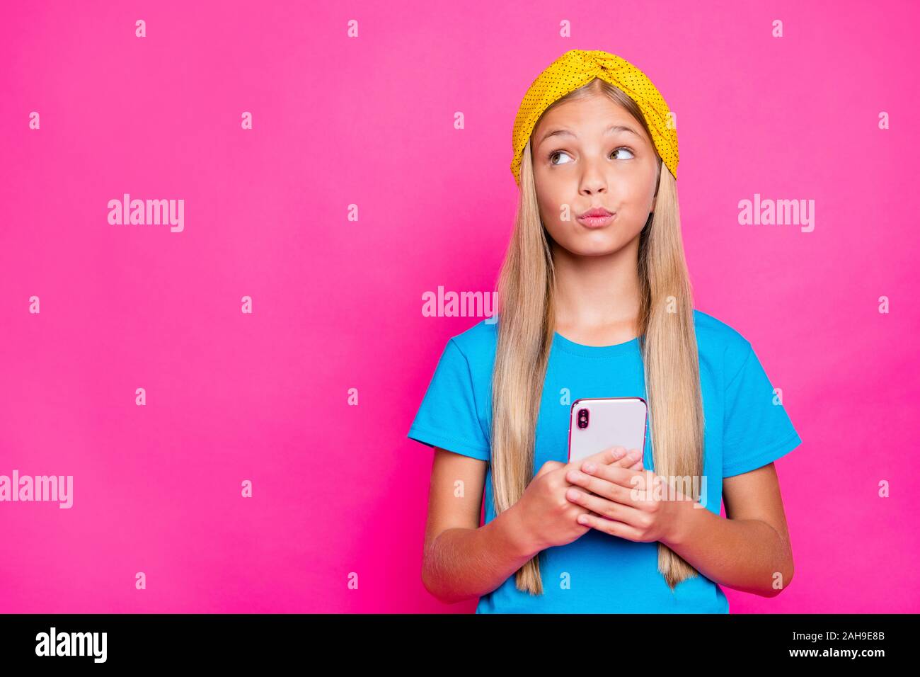 Portrait de jeune fille rêveuse utiliser son téléphone auto lire blog feedback pensez à question difficile, porter un tee-shirt bleu couleur rose plus isolés vêtements retour Banque D'Images