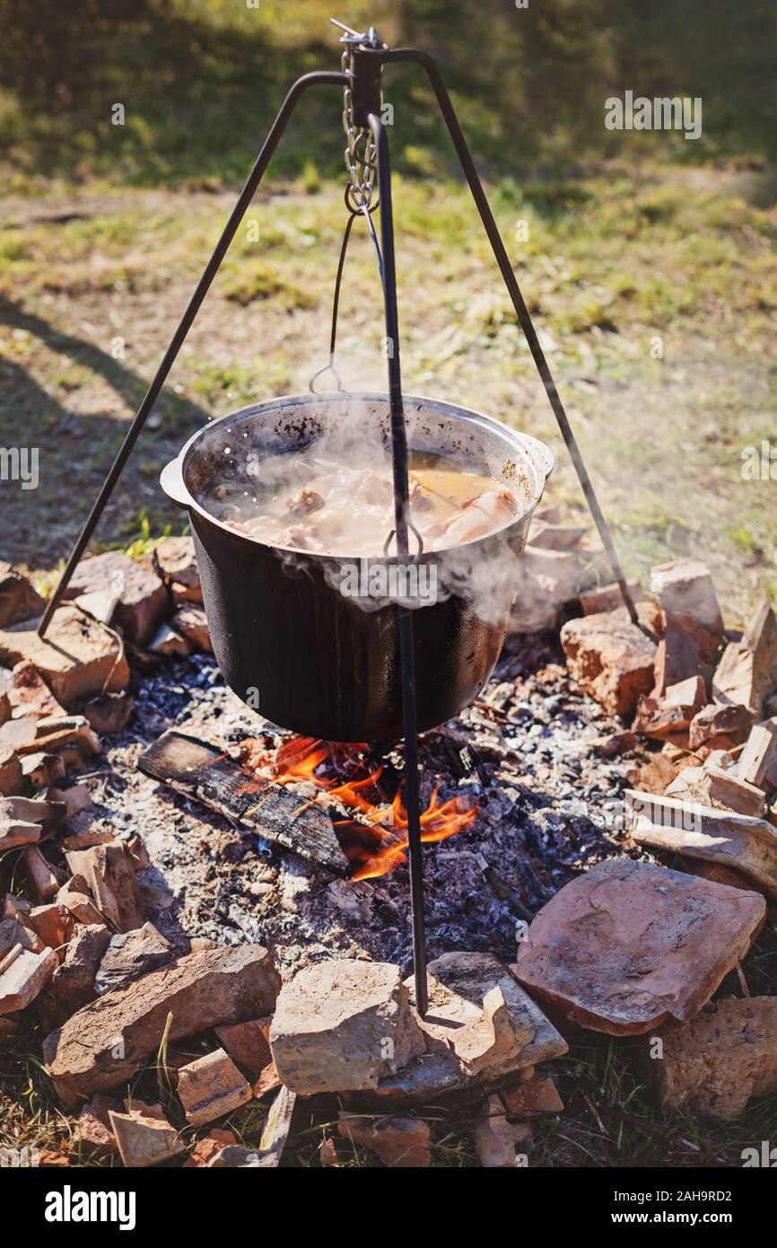 Cuire le dîner en grand chaudron sur feu de camping. Jour d'été ensoleillé Banque D'Images